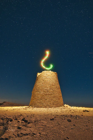 Stone tower under starry night sky with light painting.