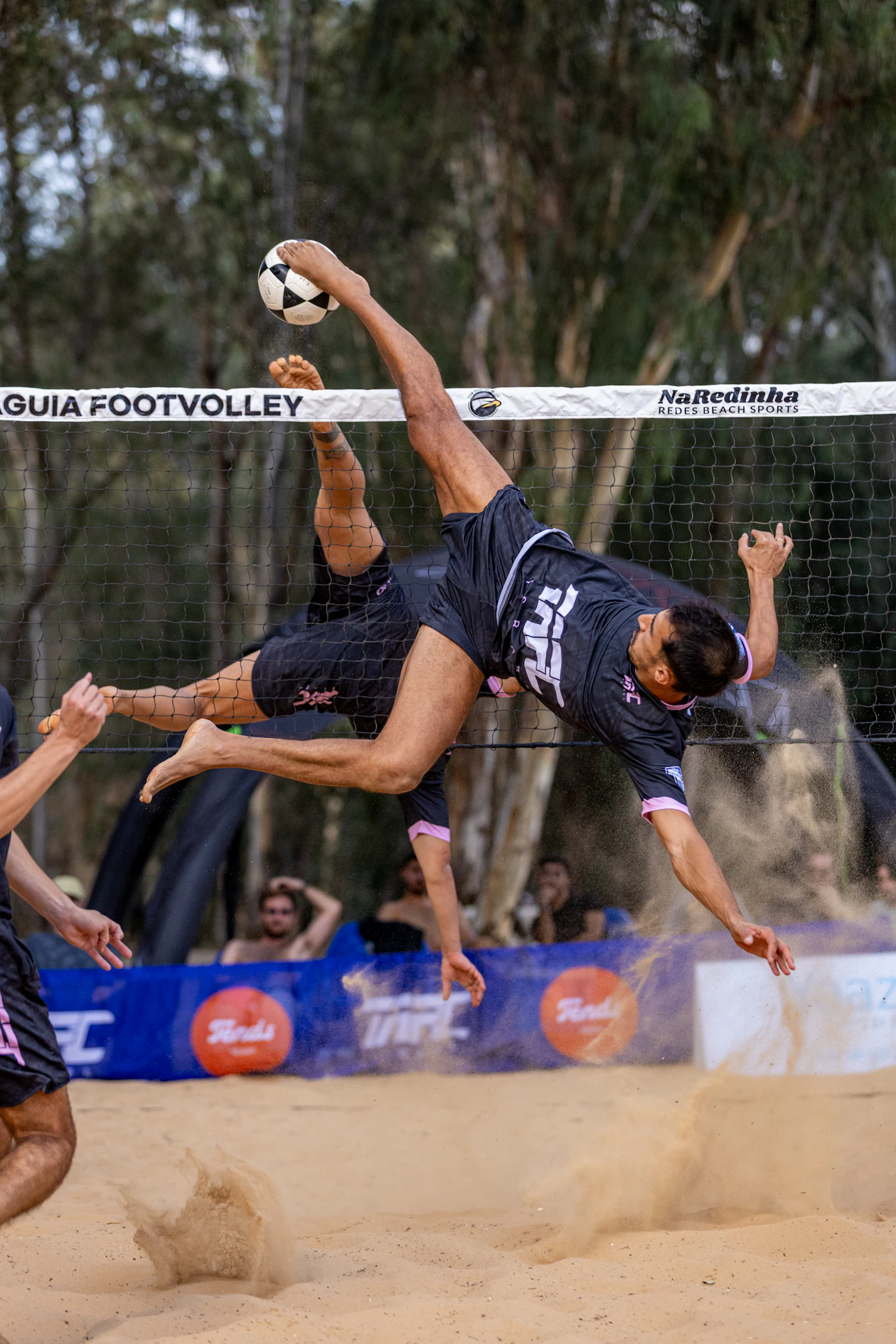 Jogadores disputando uma partida de futevôlei em uma quadra de areia