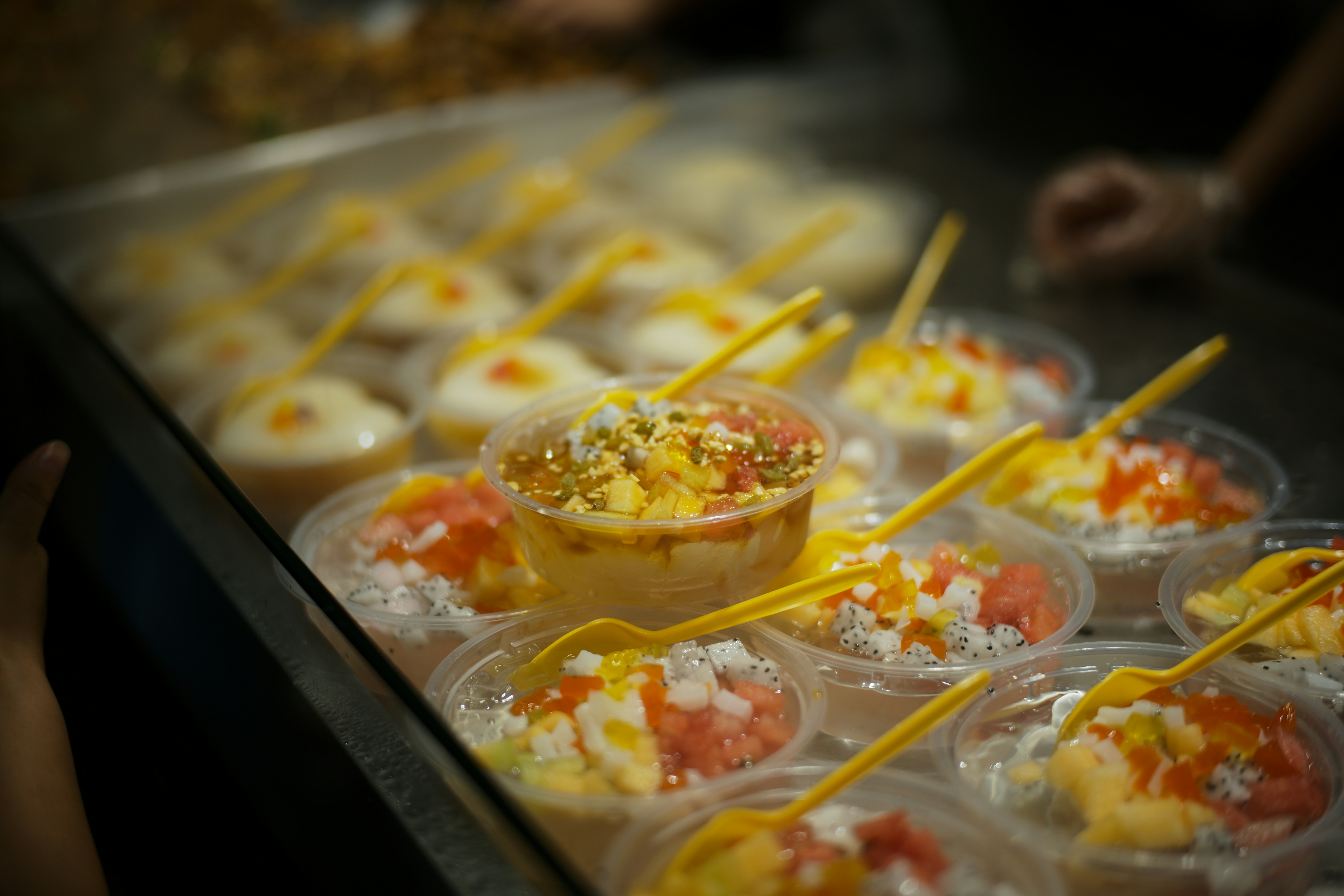 Pequenos copos de comida colorida com colheres amarelas.