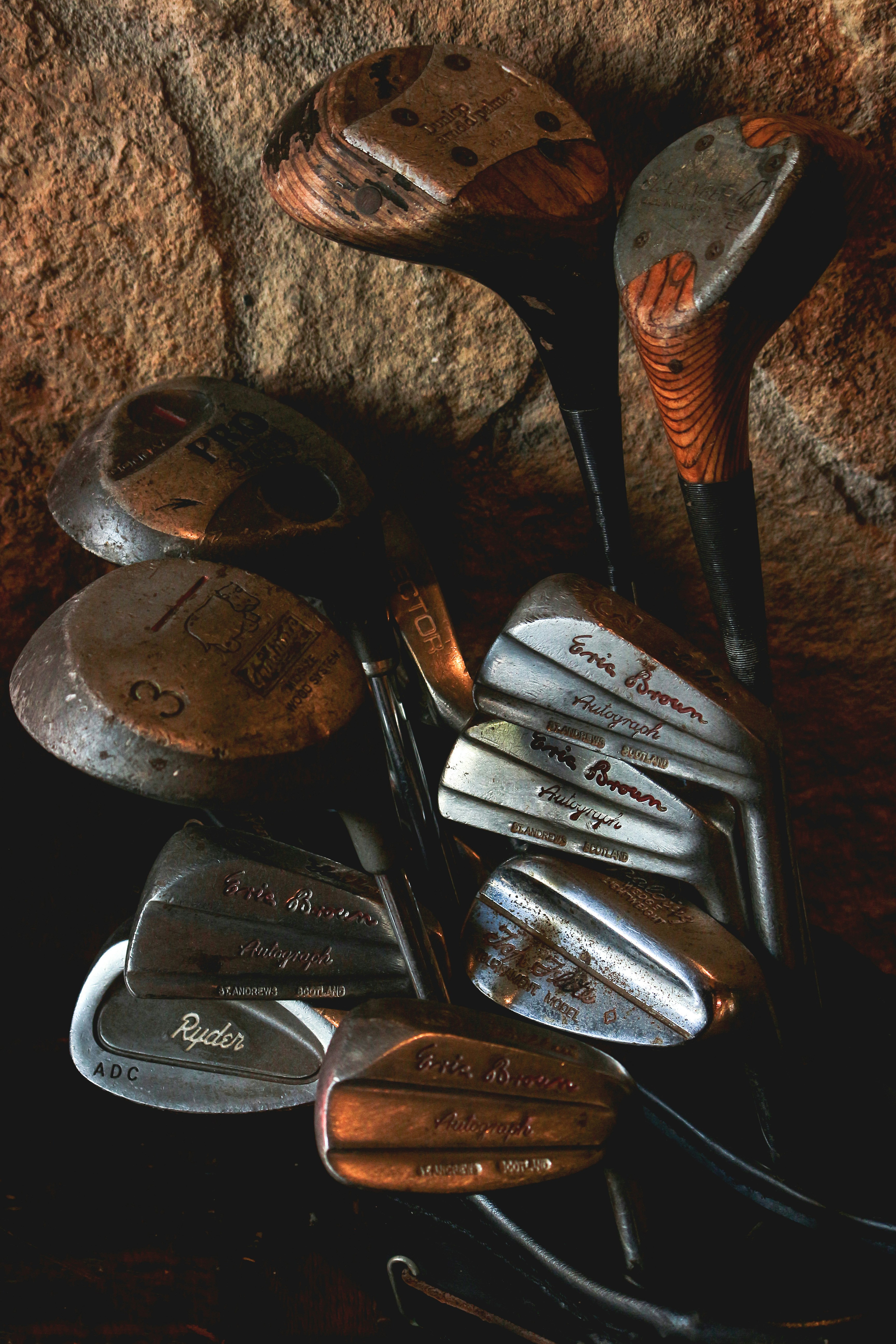 Vintage golf clubs resting against a stone wall