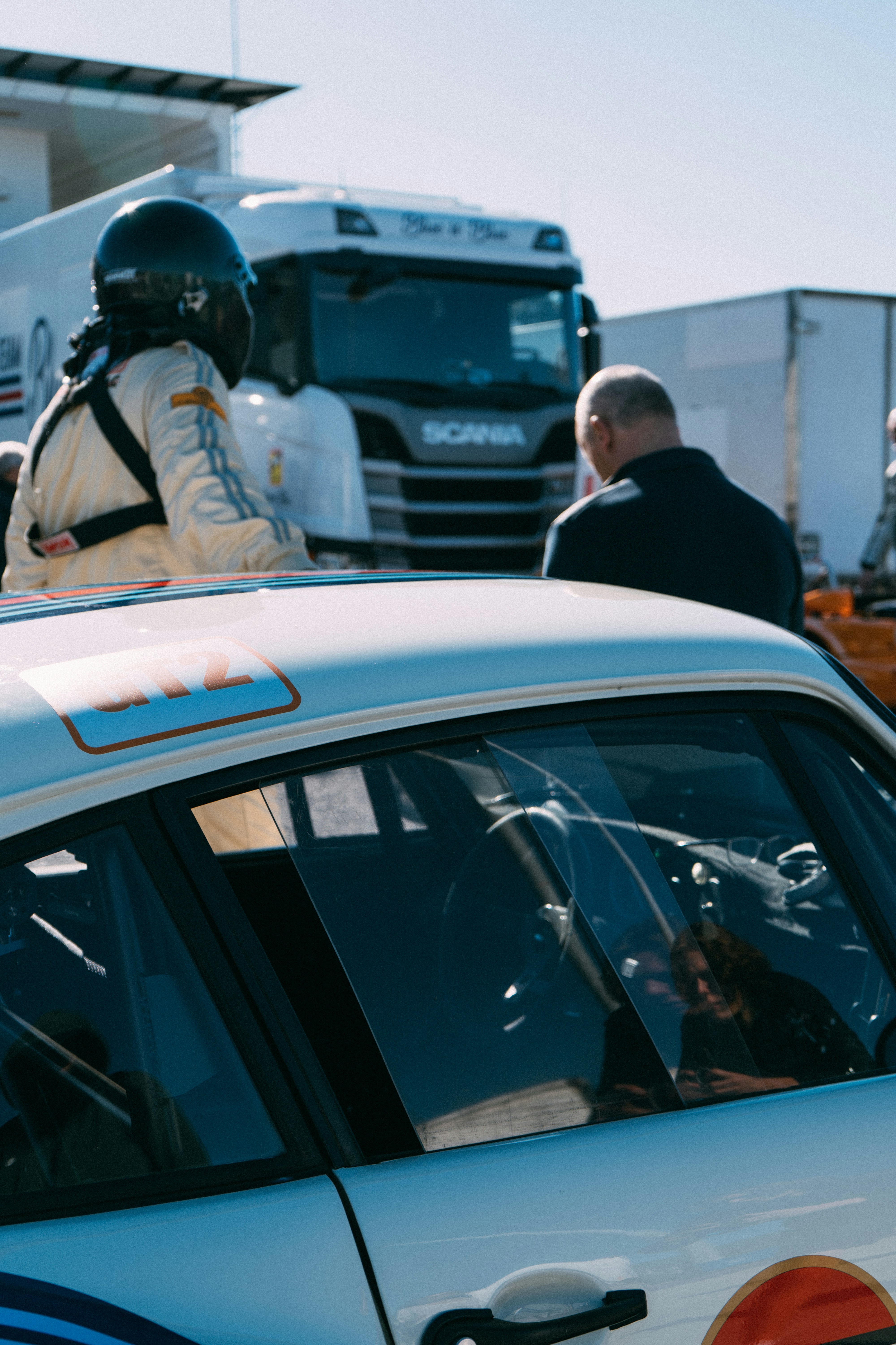 Race car driver and man talking by truck