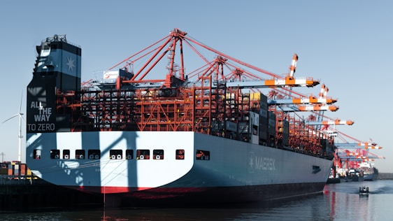 Large cargo ship docked at a port with cranes