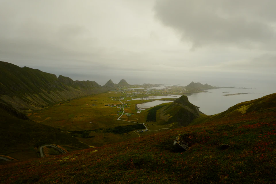 Mountainous landscape with town at hill's base and large body of water to right