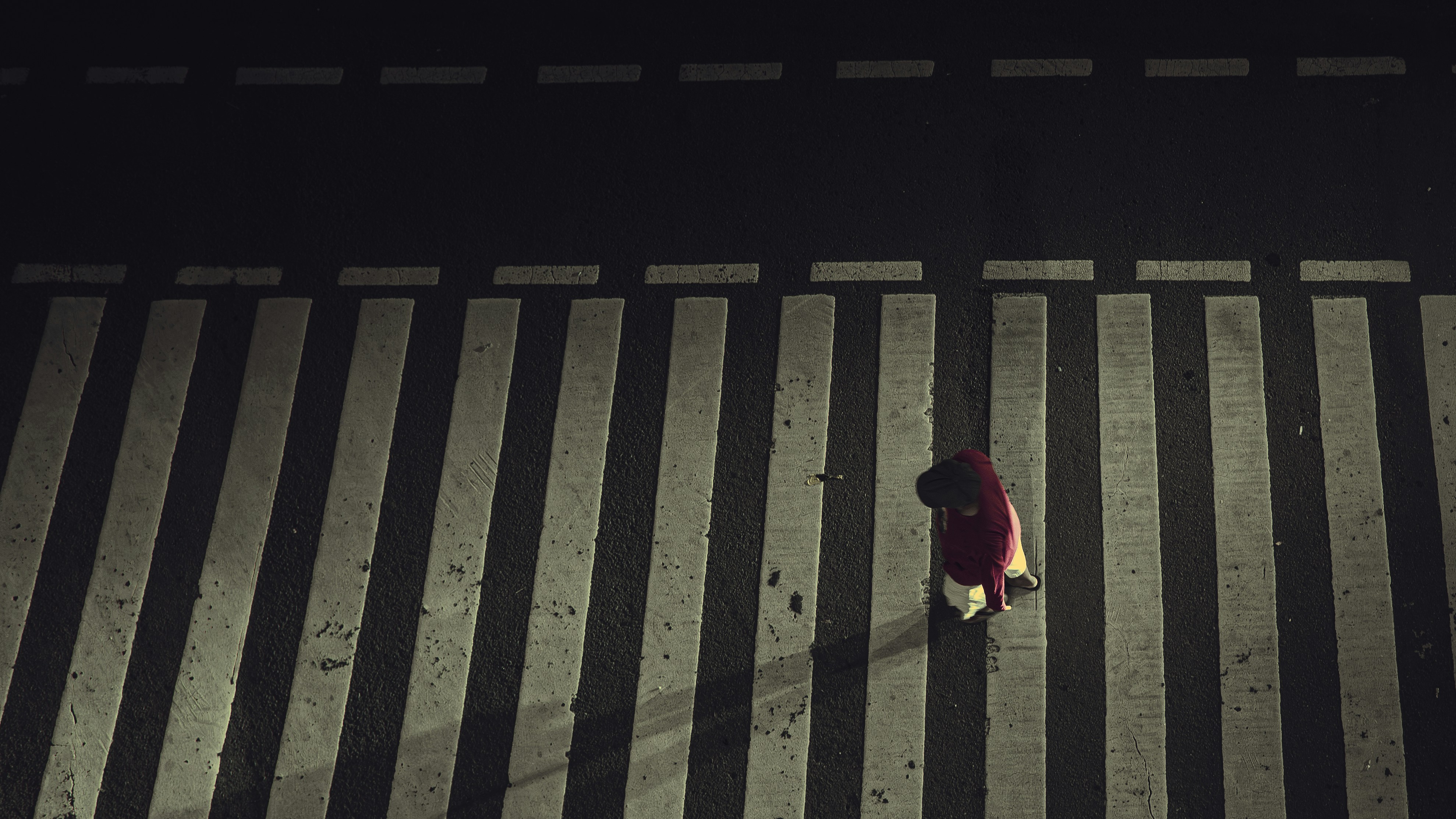 Person in red coat on a crosswalk at night