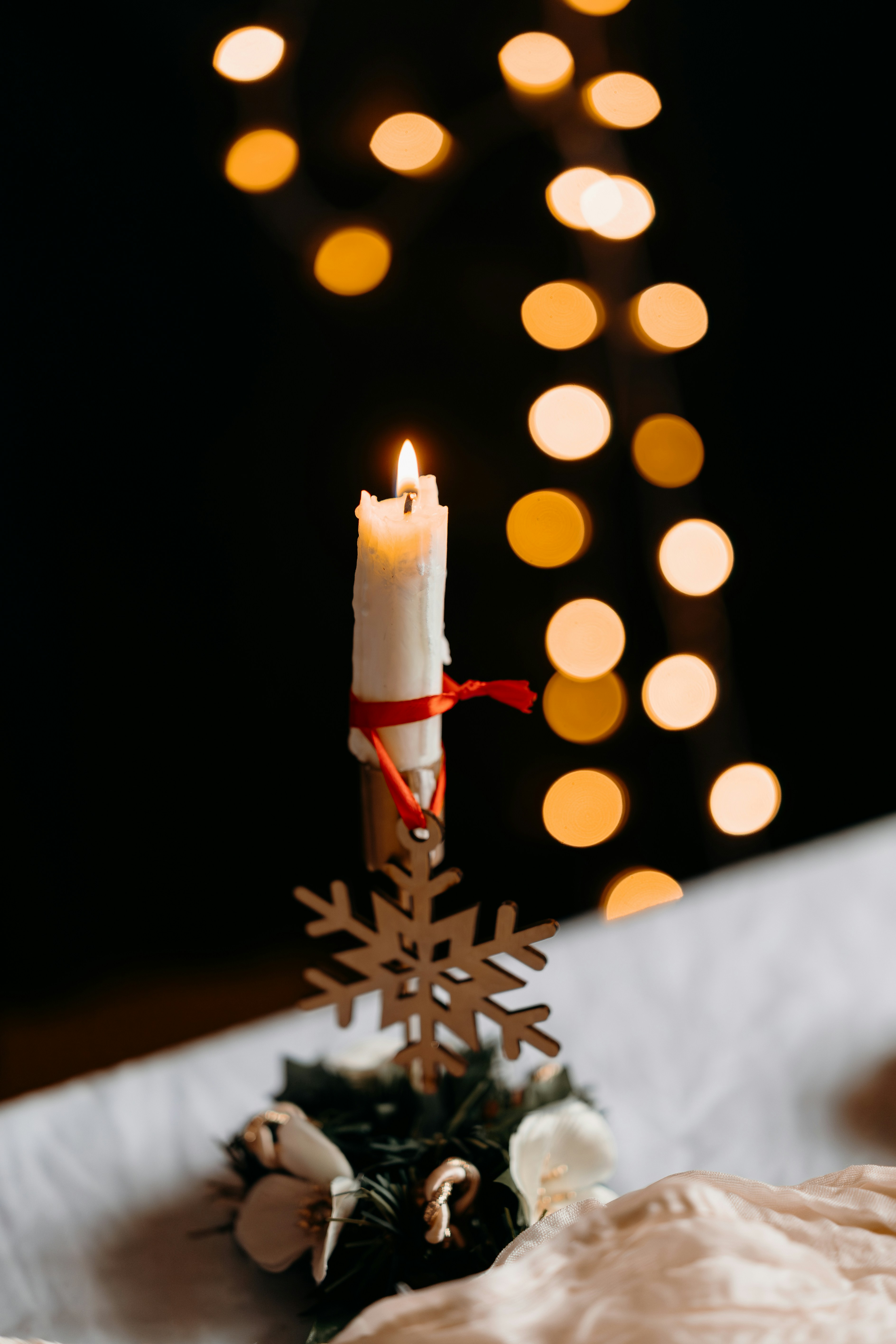 A lit candle with a snowflake decoration.