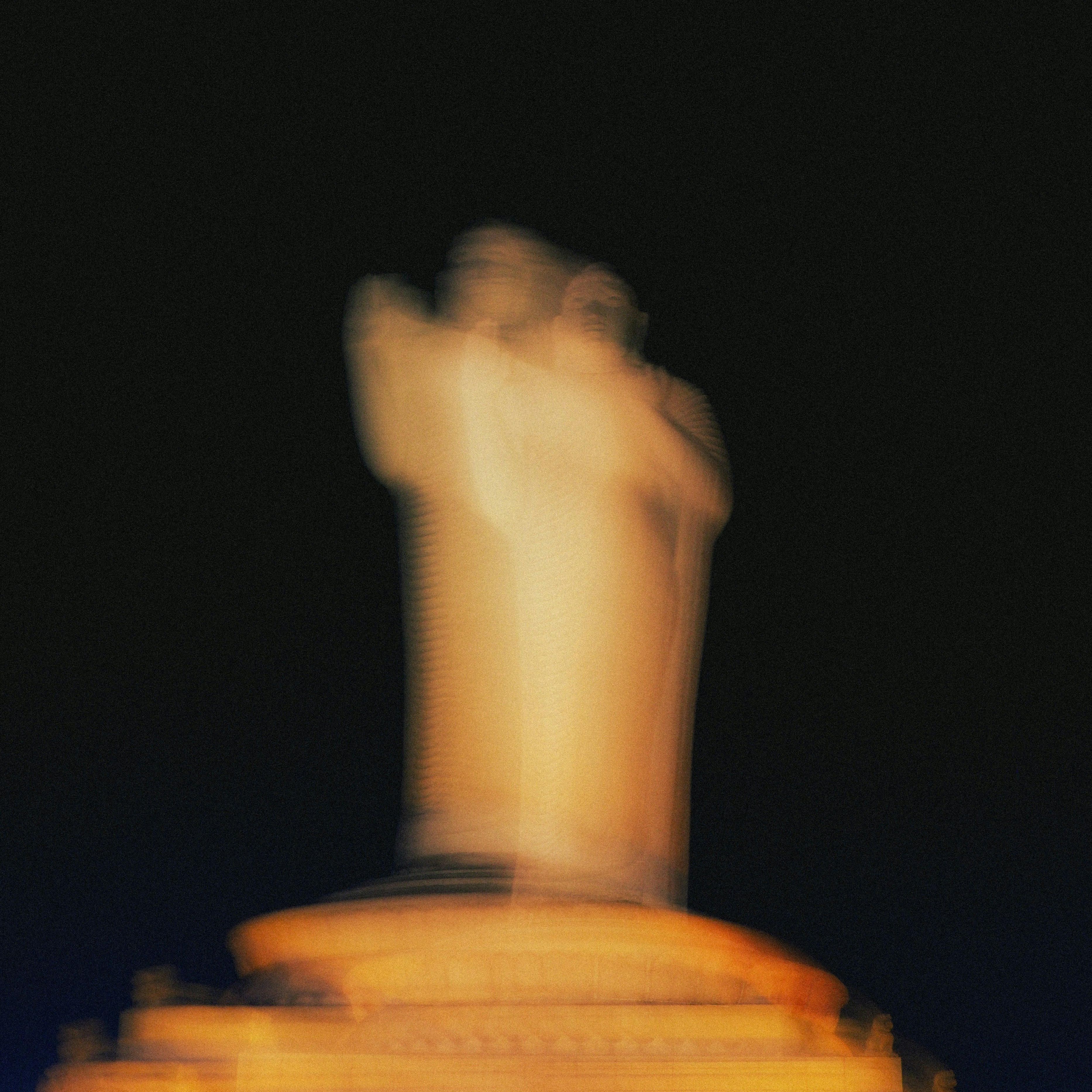 Blurred statue illuminated against a dark sky
