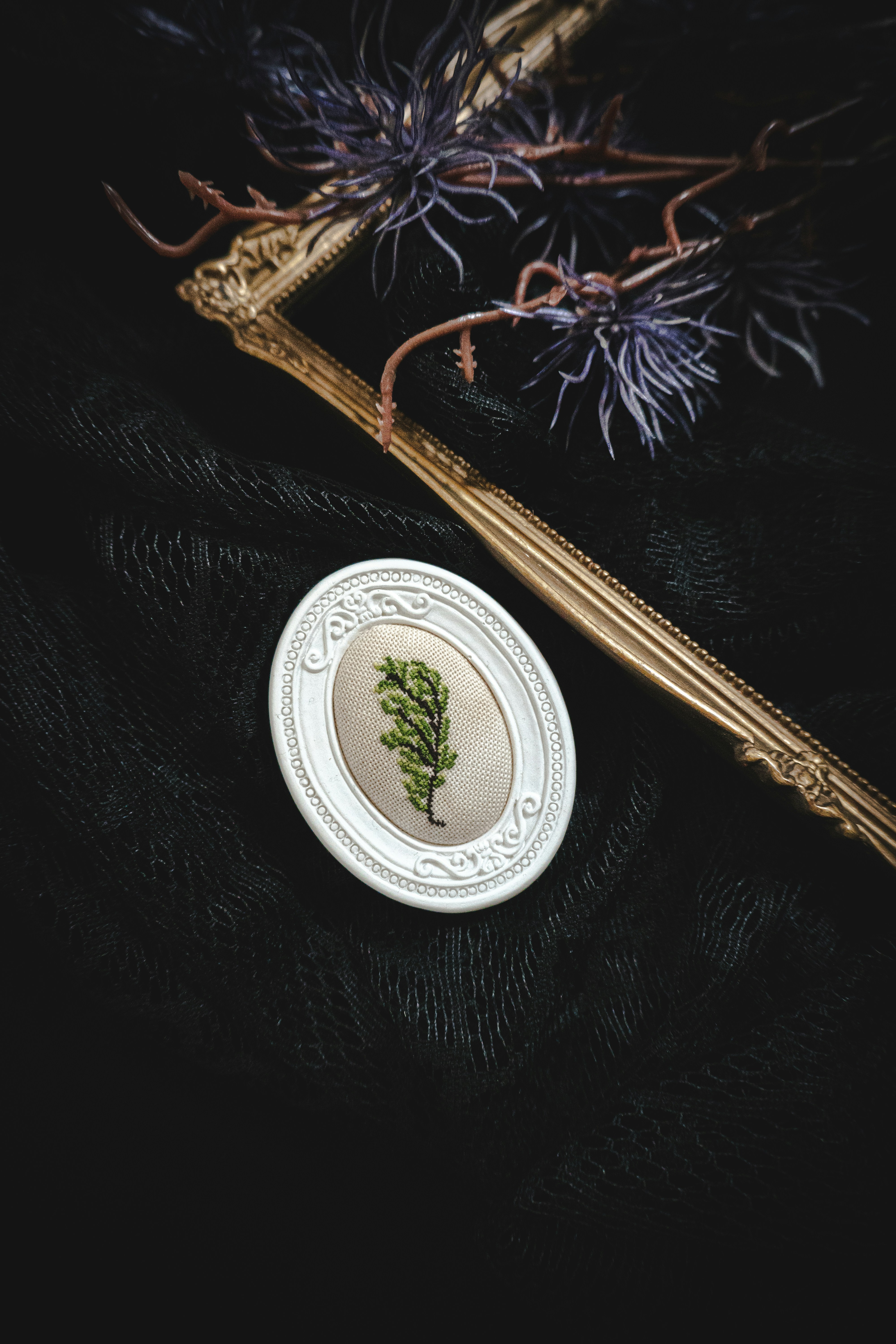 Oval frame with green sprig on black fabric