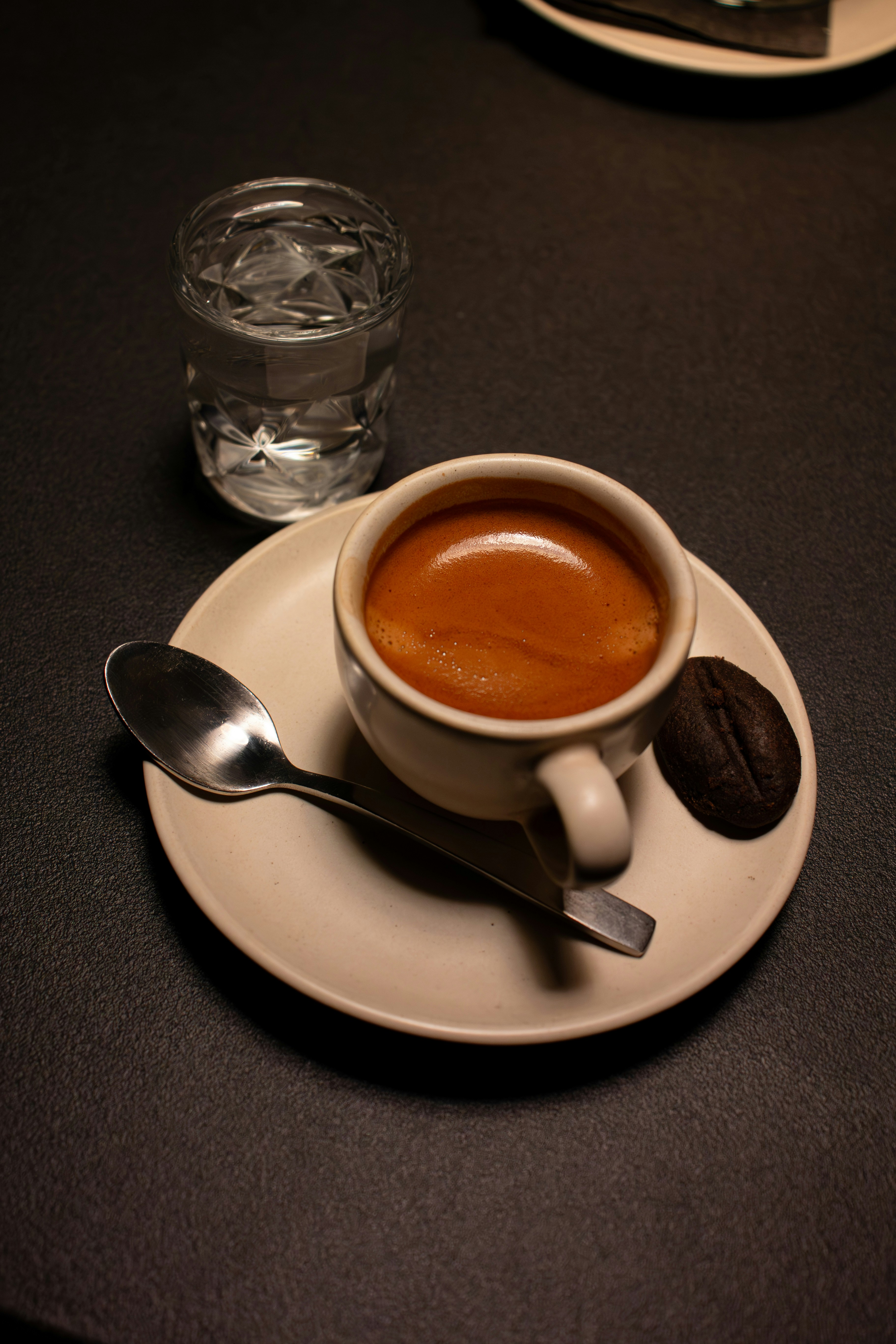 Espresso mit einem Keks und Wasser auf einer Untertasse
