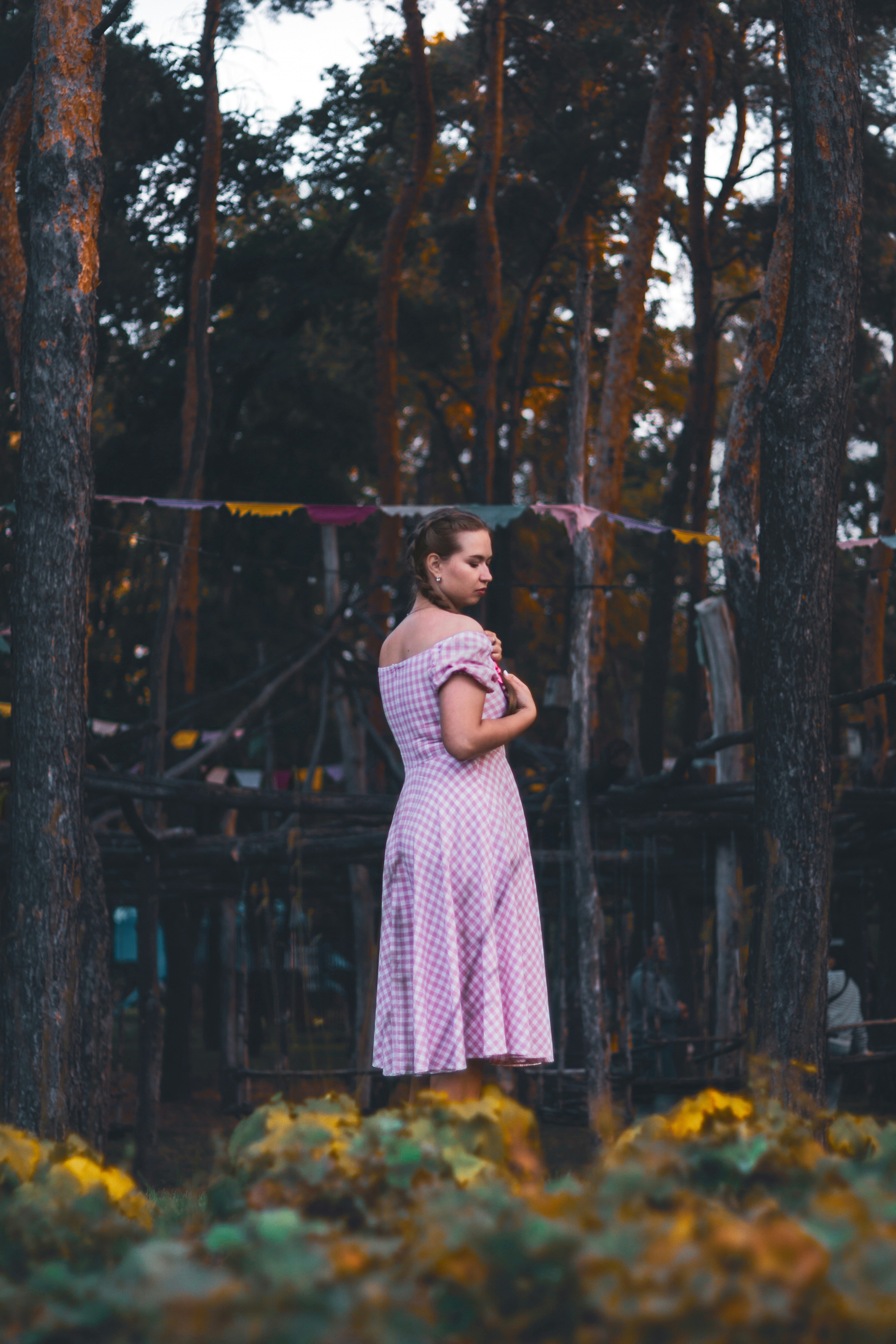 Femme en robe rose debout dans la forêt