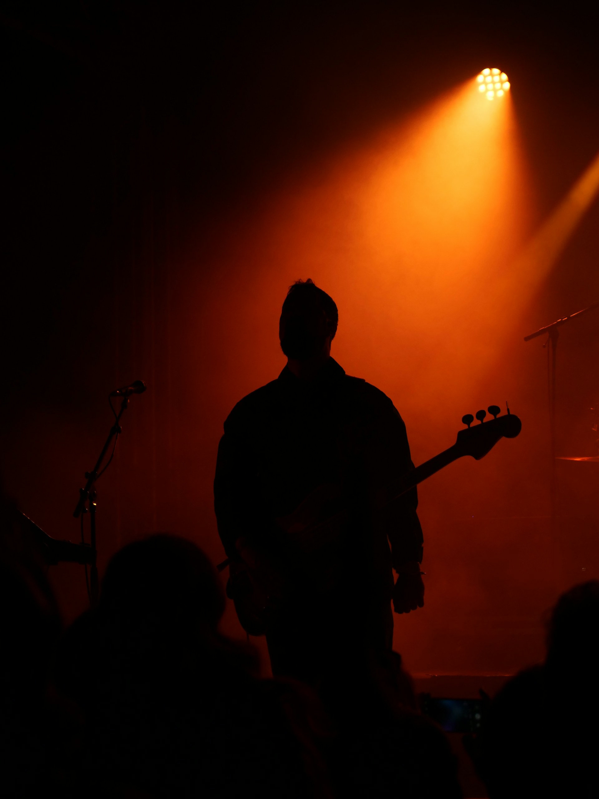 Silhouette of a guitarist on stage with orange spotlight.