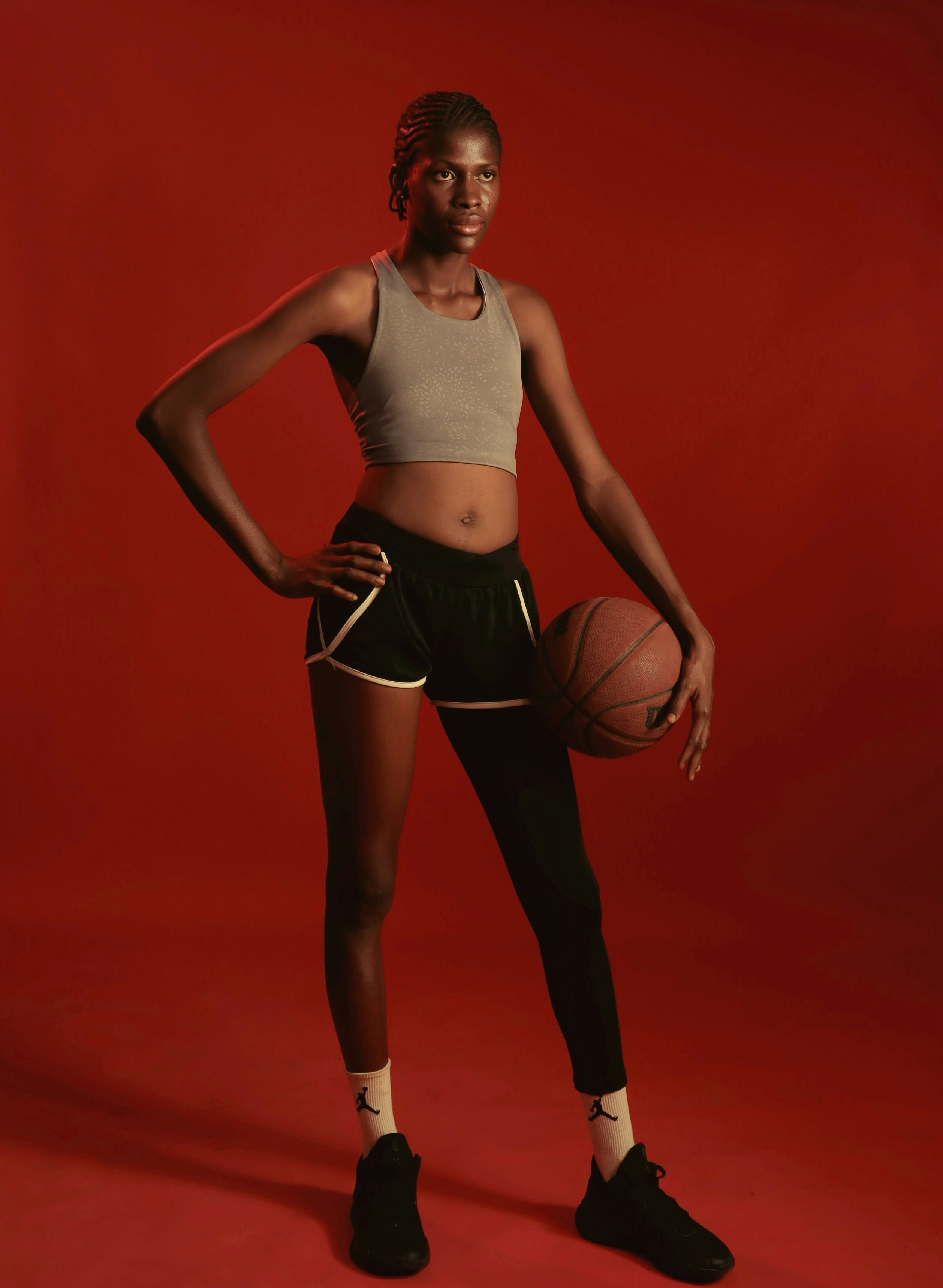 A tall woman in athletic wear holds a basketball