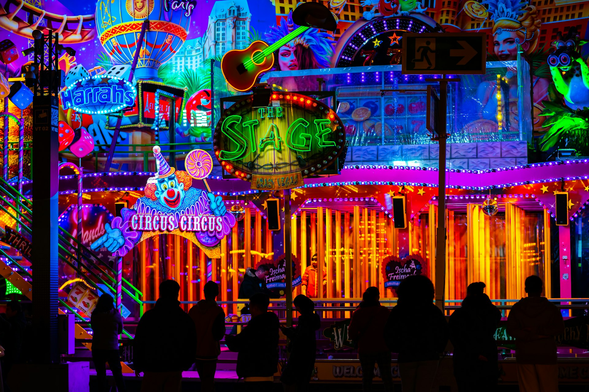 Brightly lit carnival rides at night with people