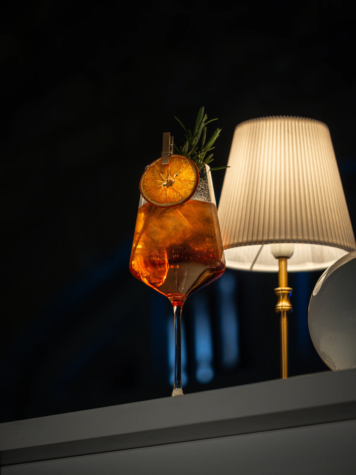 Cocktail garnished with an orange slice and a rosemary sprig