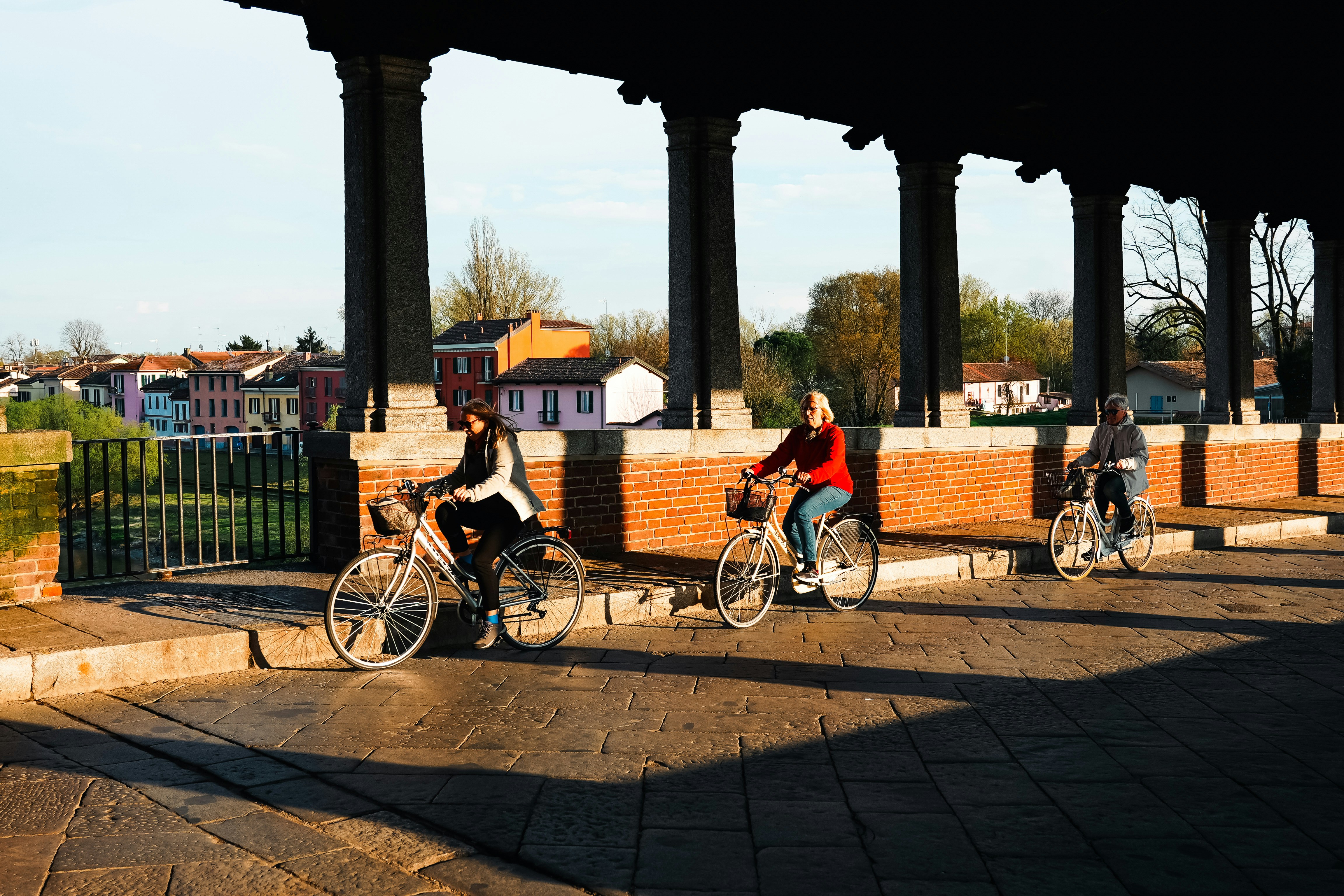 Three people cycling under a covered walkway