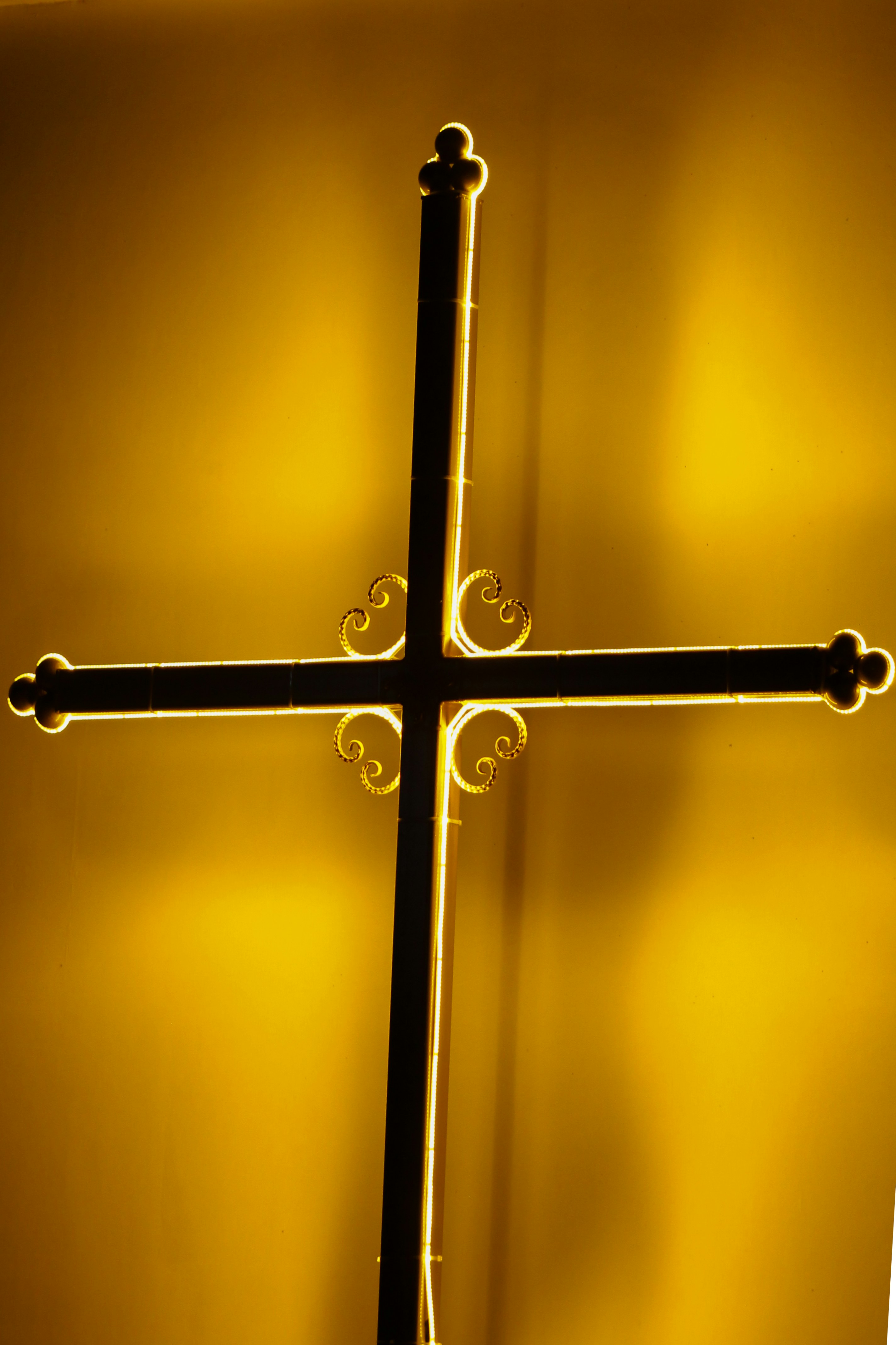 Uma cruz escura silhuetada contra um fundo amarelo brilhante