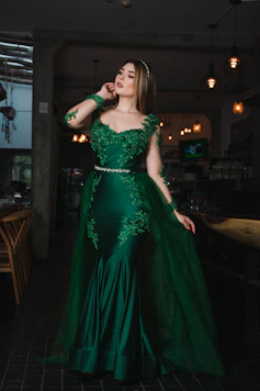 Woman in elegant emerald green gown with lace details.
