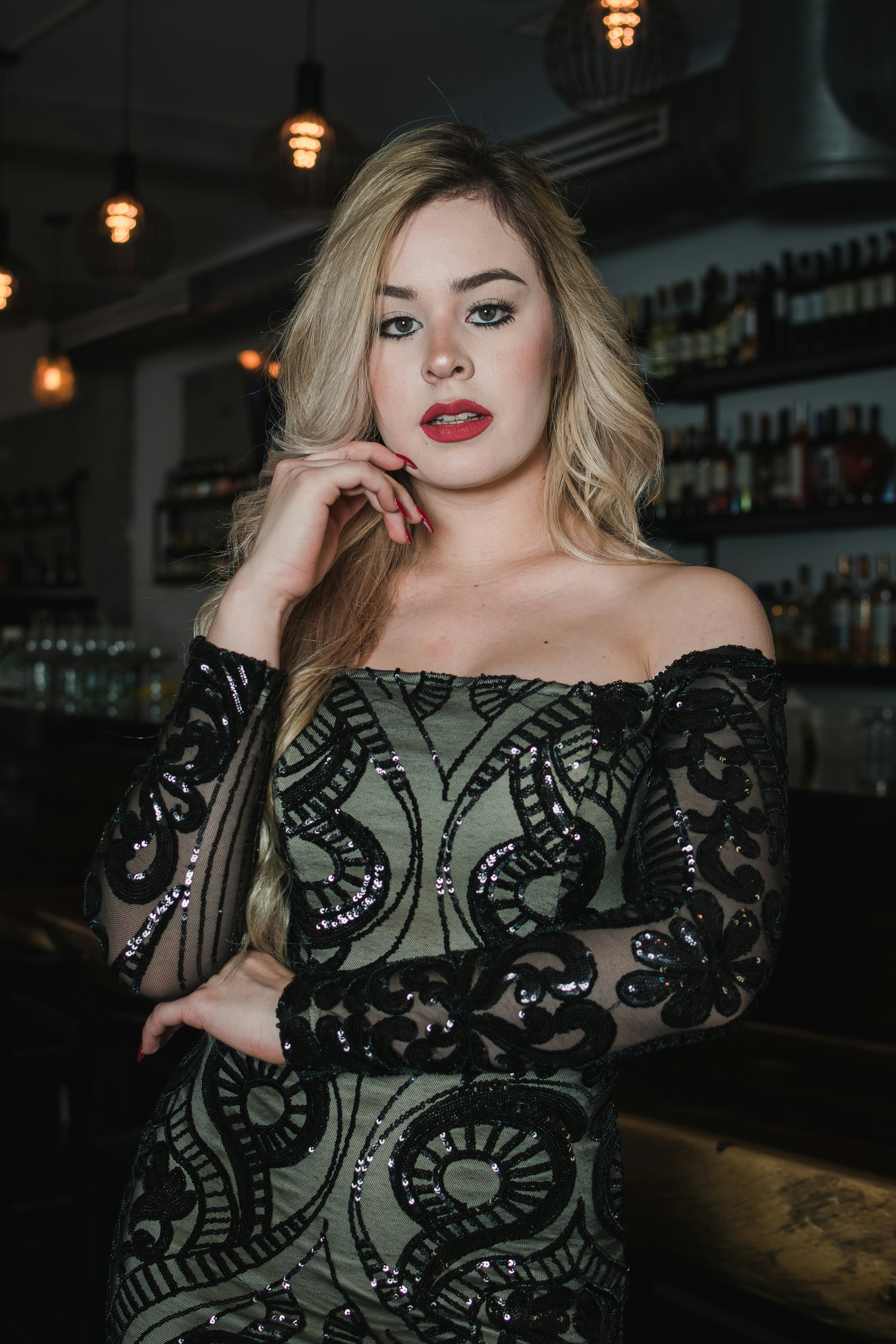 Blonde woman in sparkling dress poses in bar