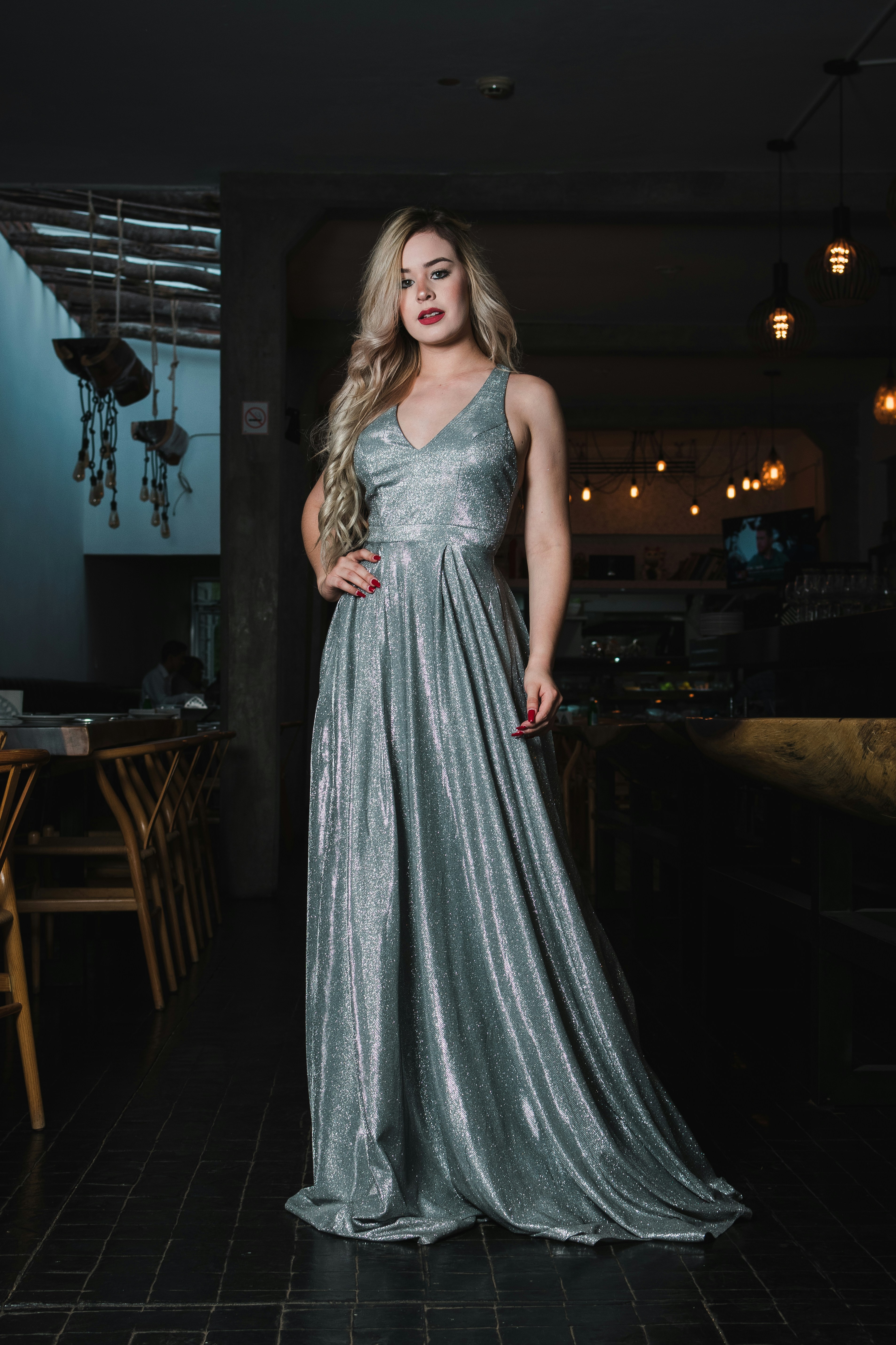 Woman in a sparkly silver dress posing indoors.