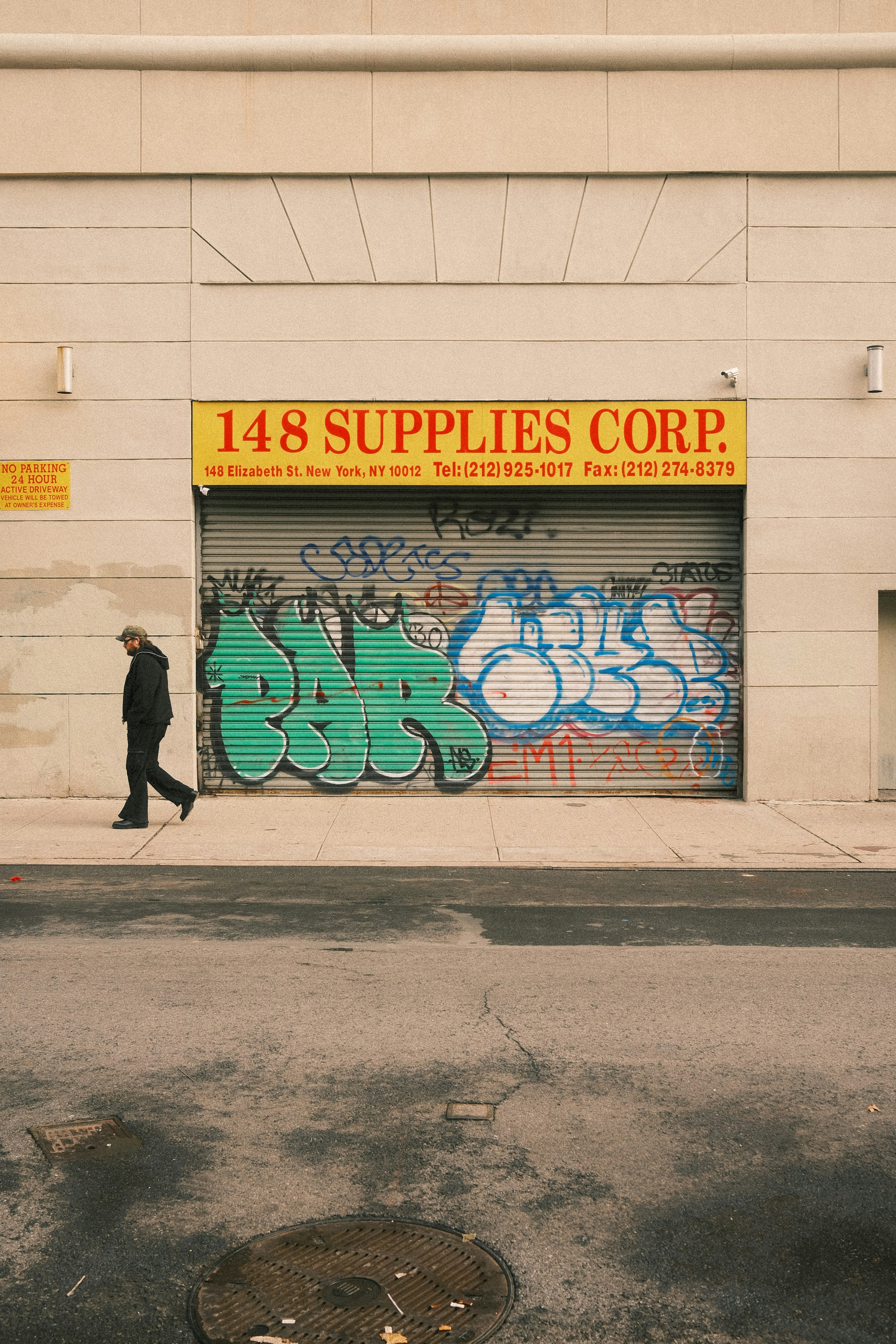 Man walks past graffiti on a closed store entrance.