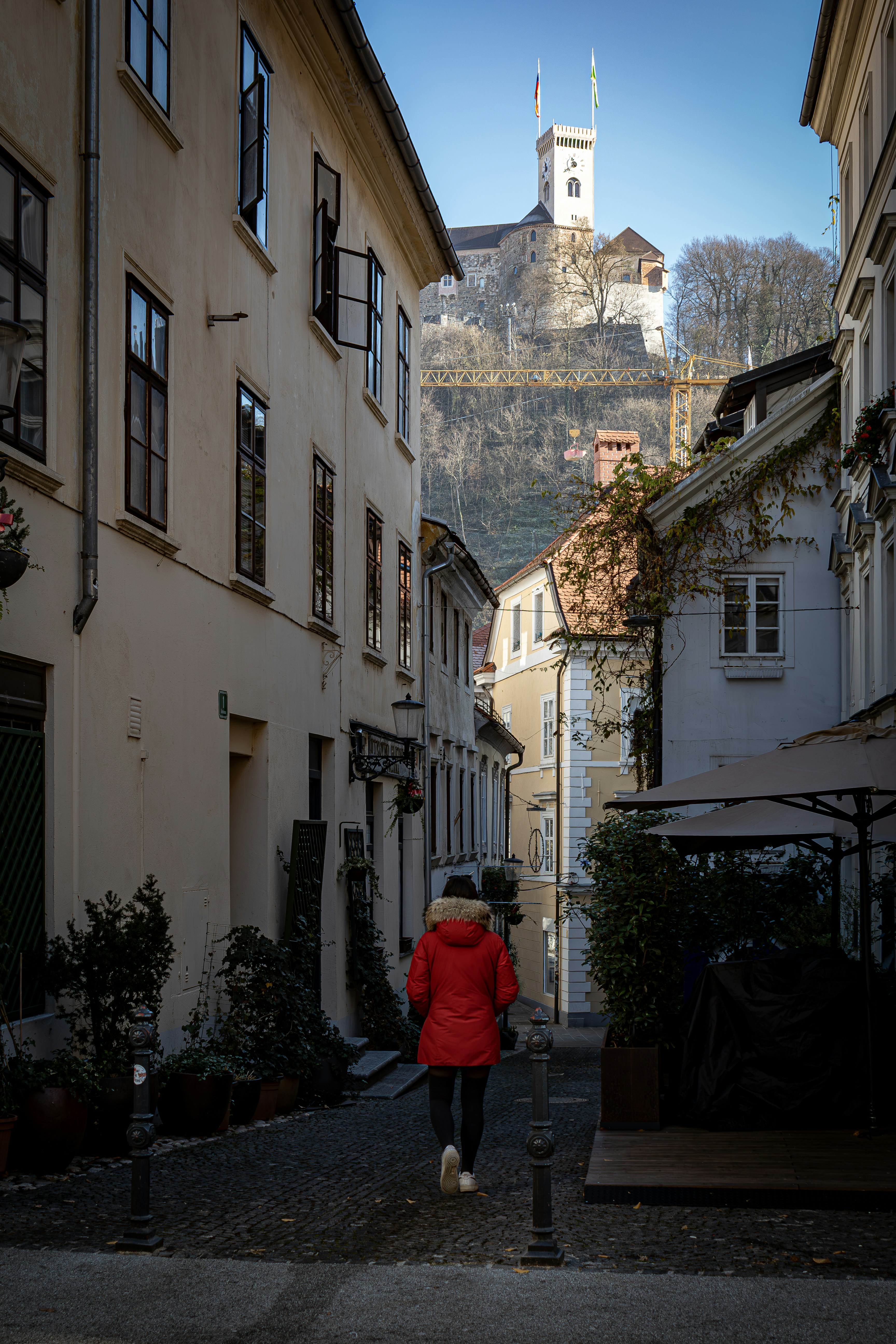 Person walks down narrow street towards castle on hill.