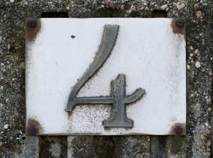 A weathered house number four on a concrete wall.