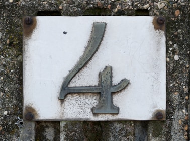 A weathered house number four on a concrete wall.
