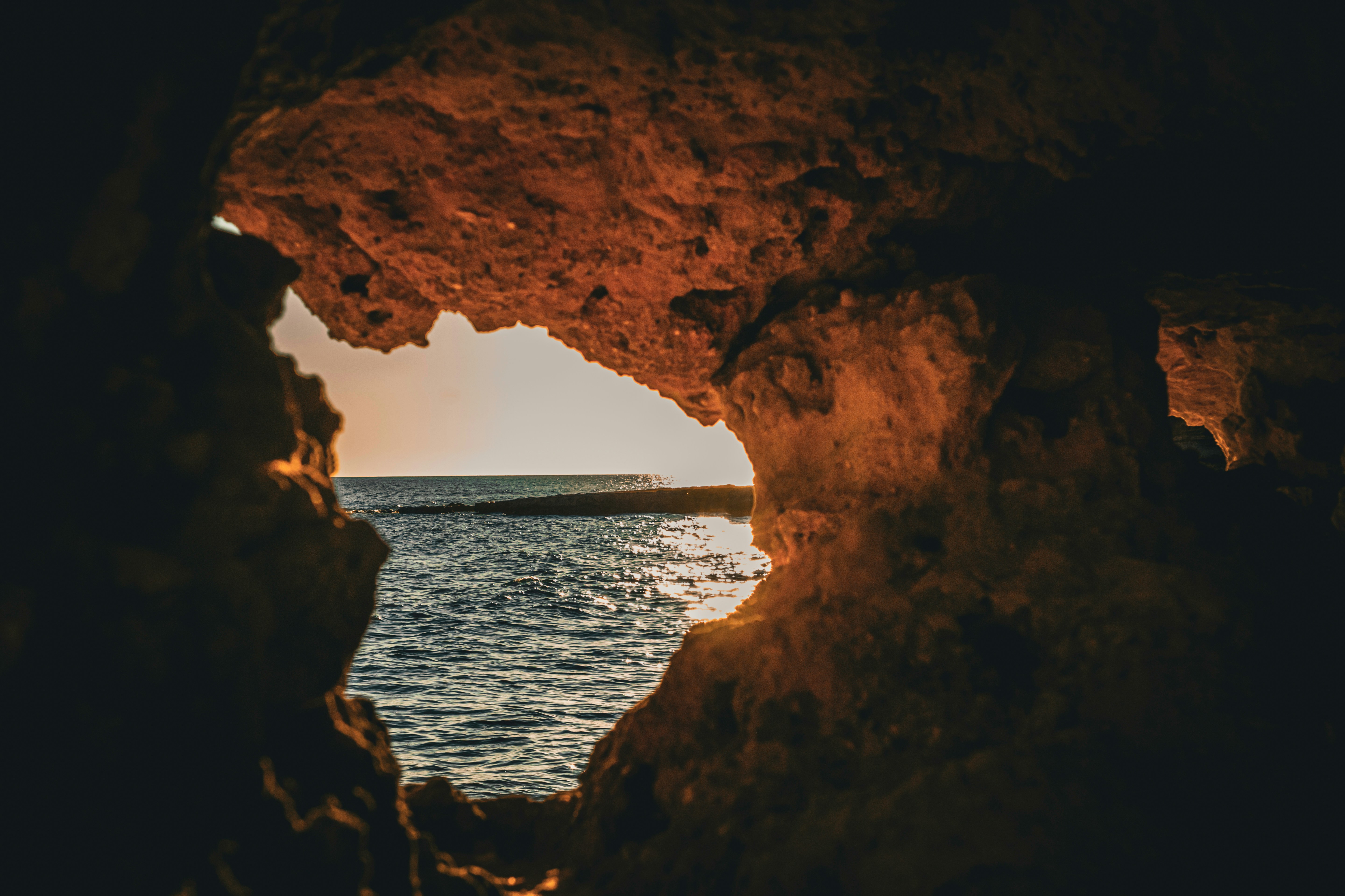 View of the ocean through a cave opening at sunset