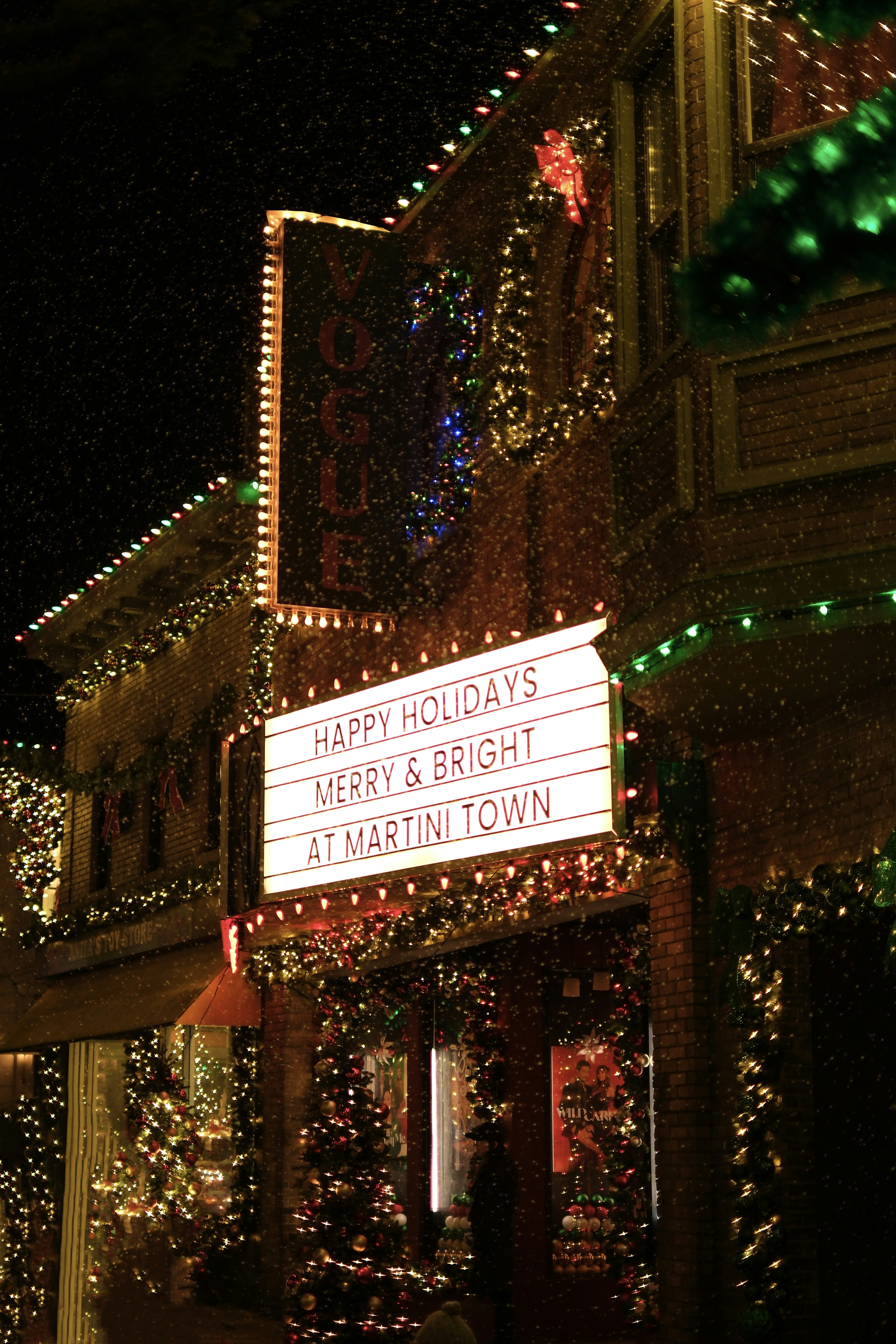 Festive holiday lights adorn building facade at night.