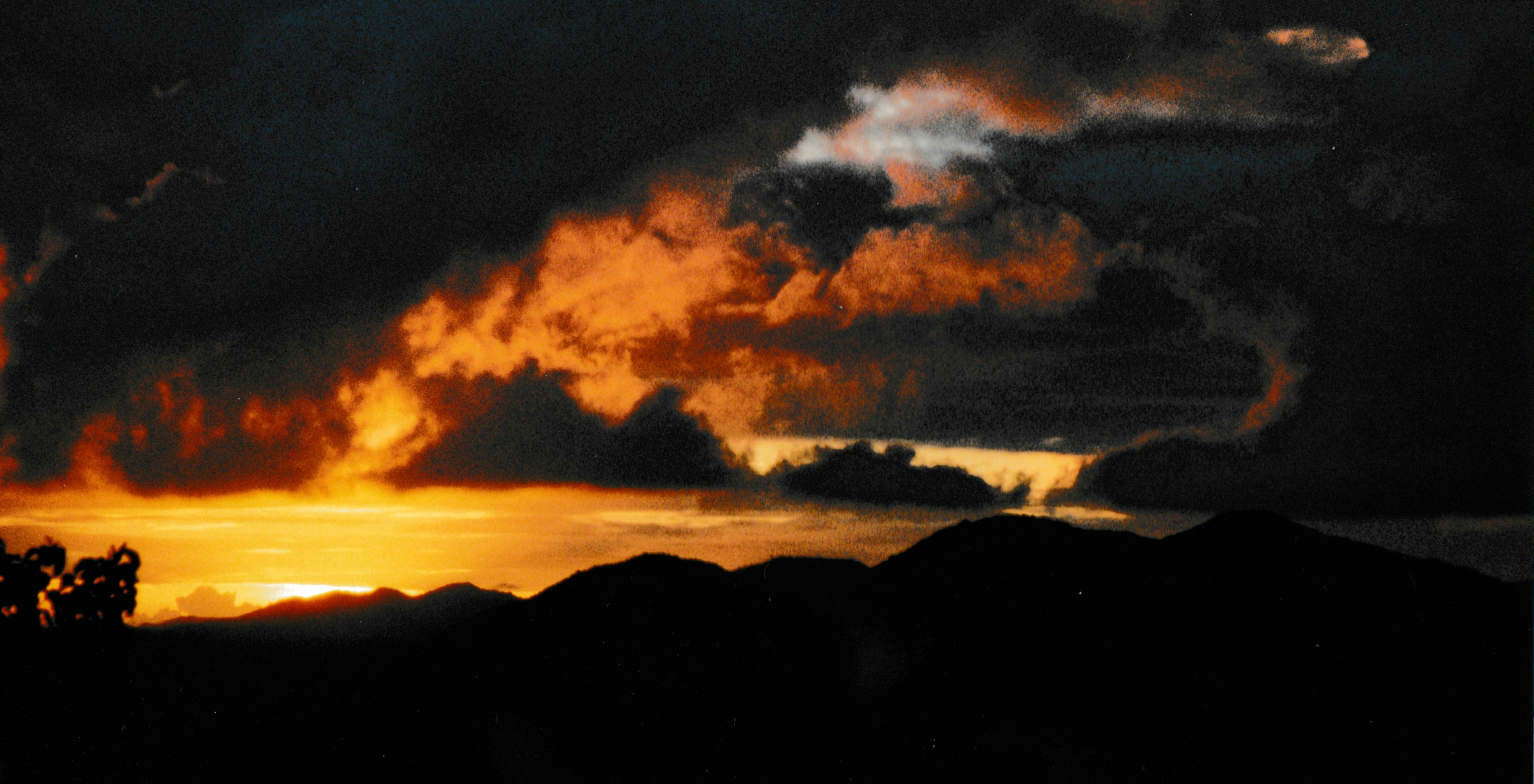 Dramatic sunset over silhouetted mountains and ocean.