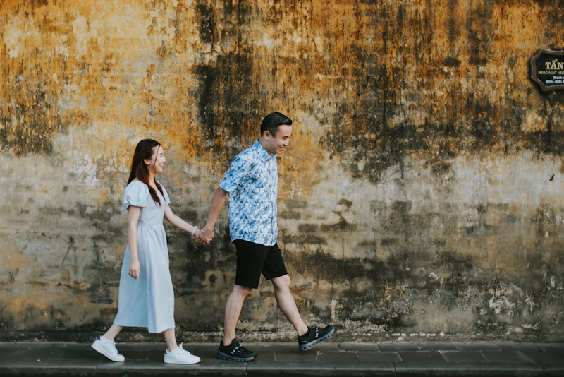 Couple walking hand-in-hand by textured wall