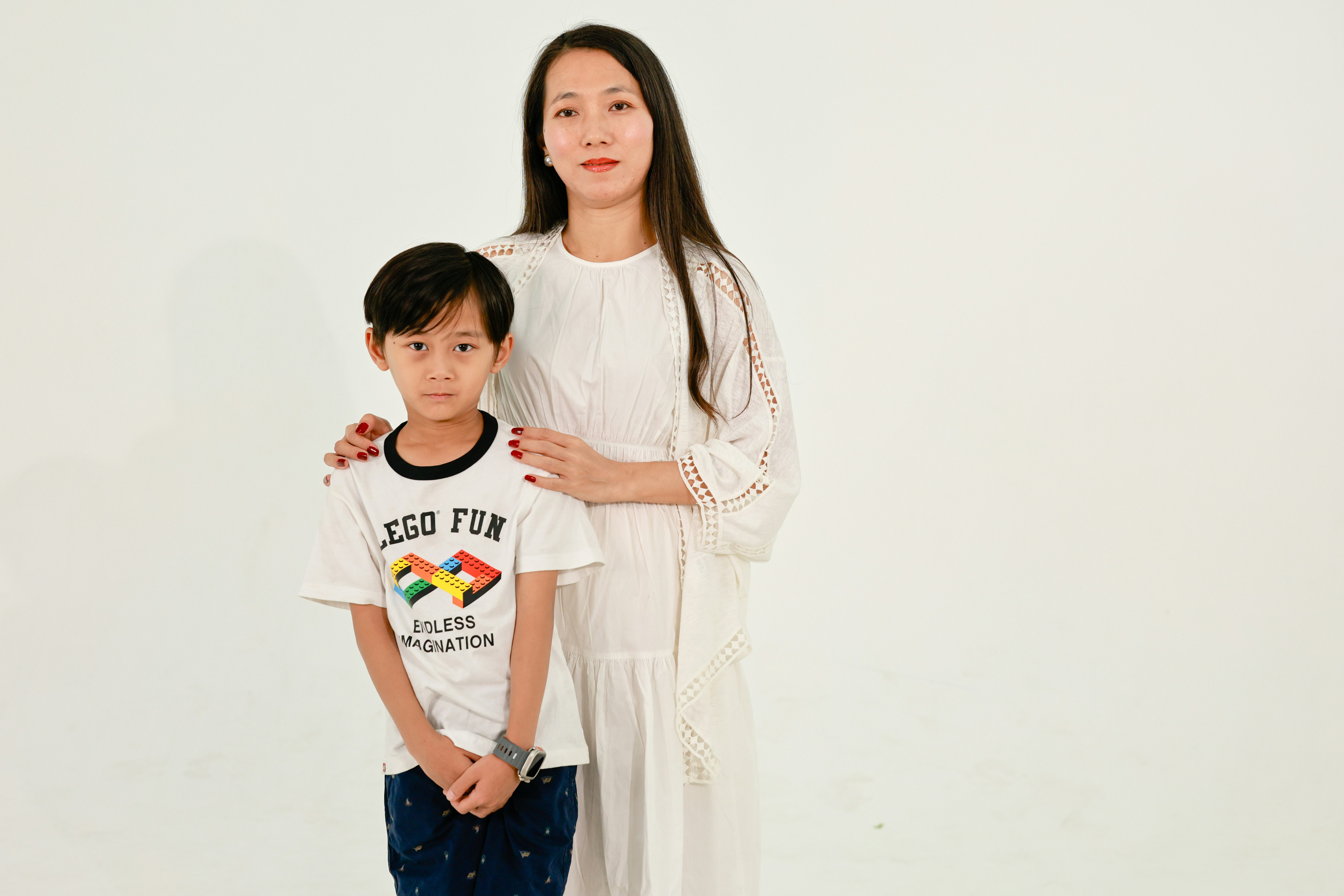 Woman and boy stand against white background