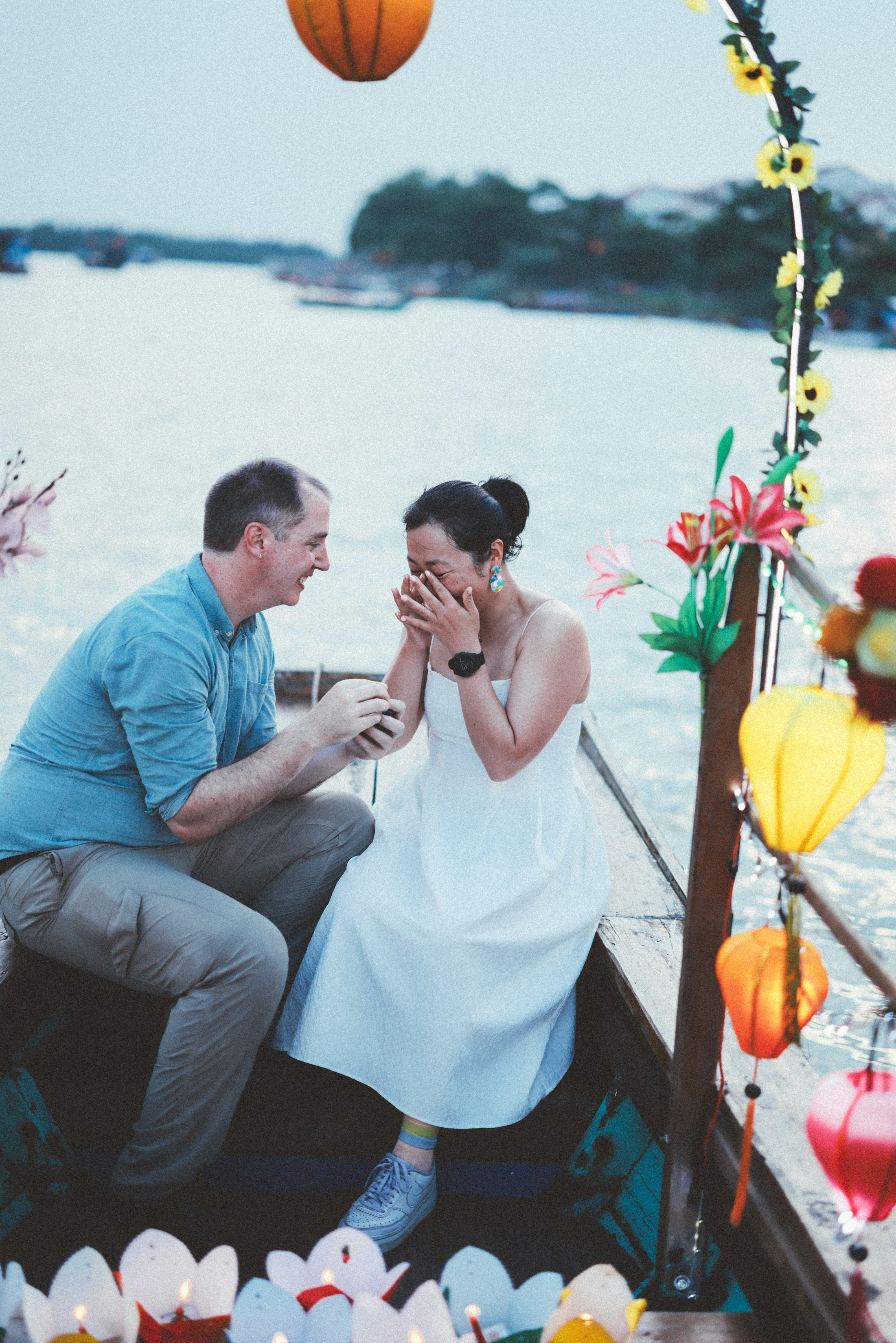Man proposes to woman on a boat at dusk.