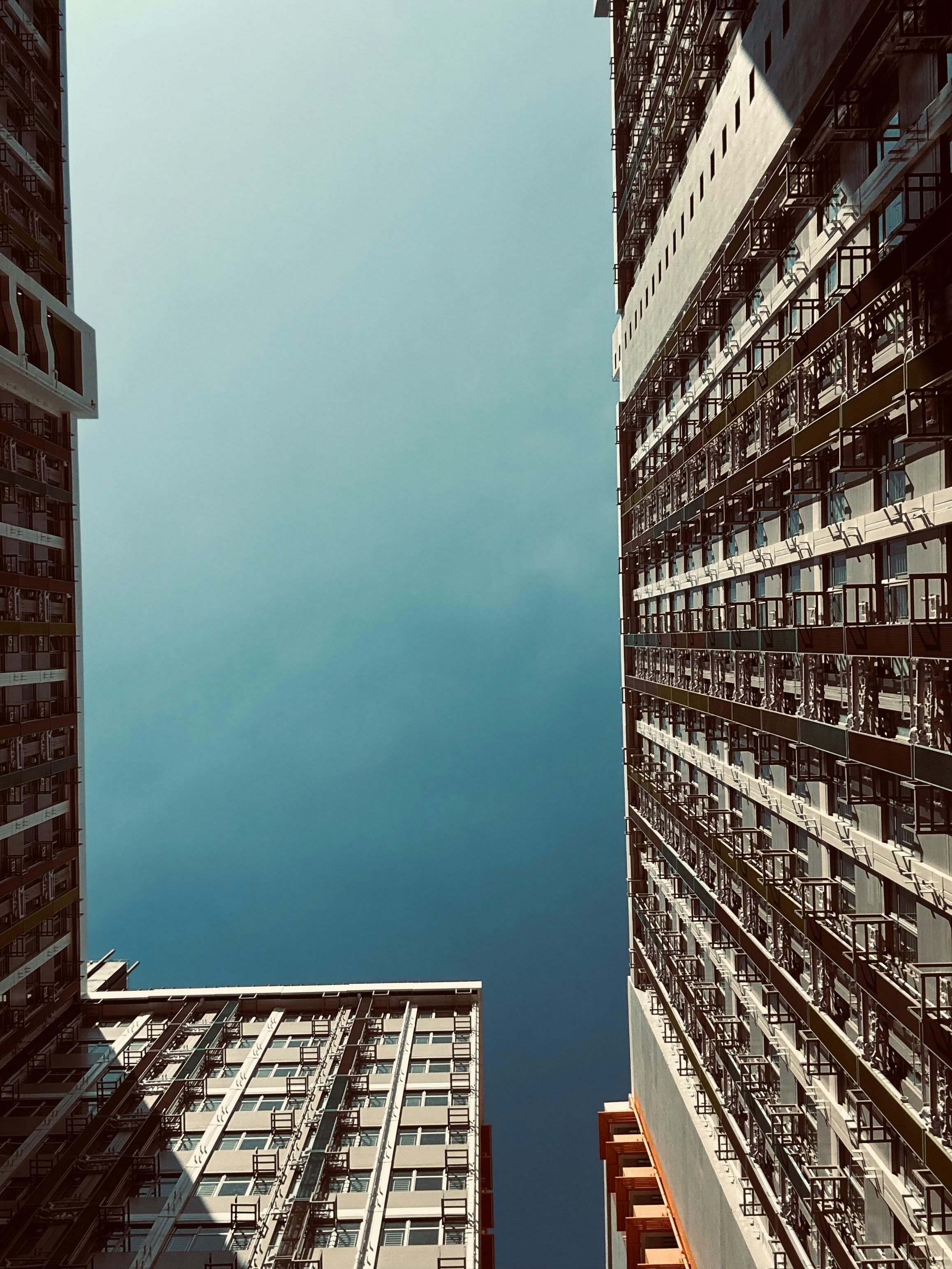 Looking up at tall buildings against a clear blue sky.