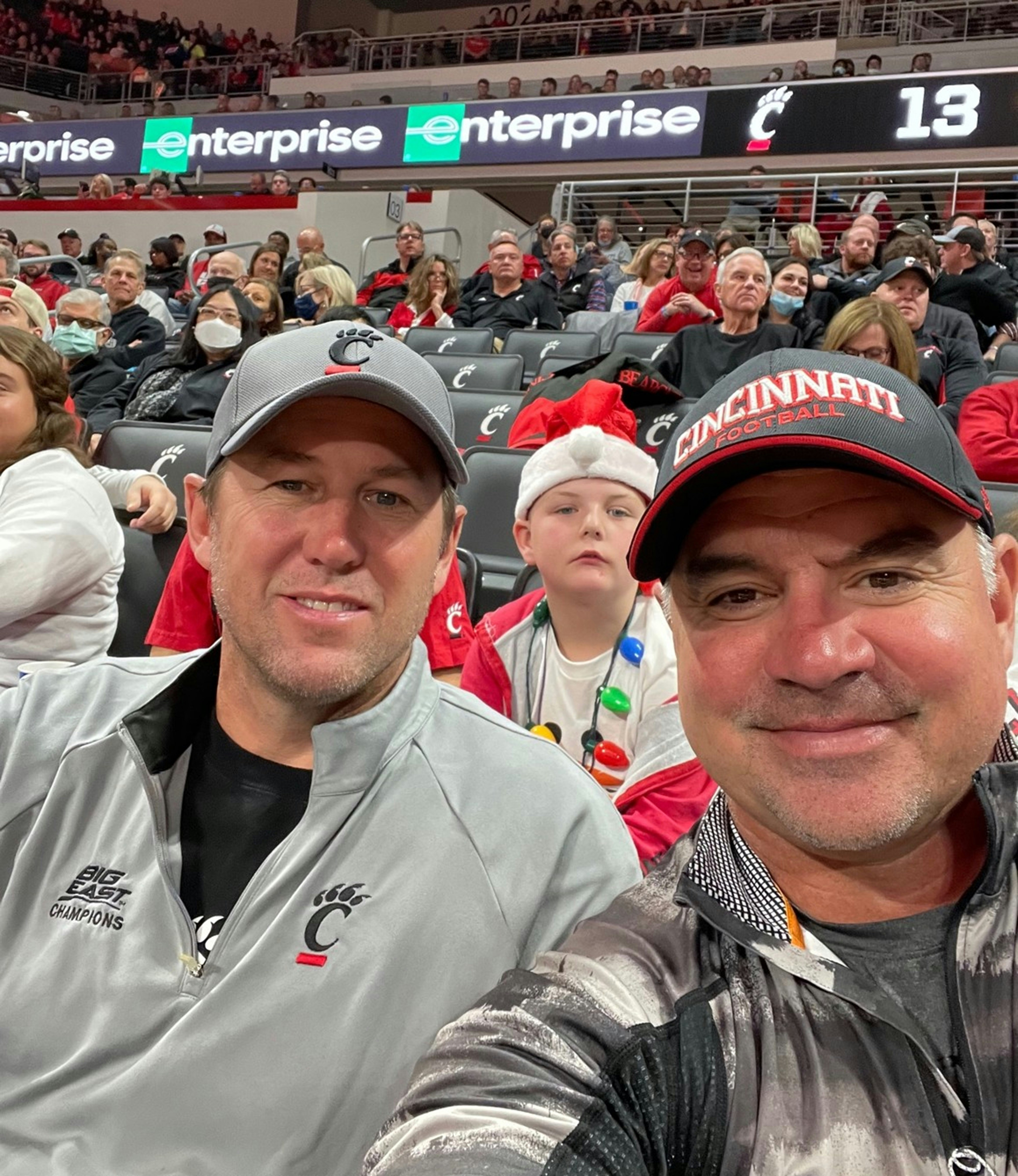 Two men in cincinnati gear at a sporting event.