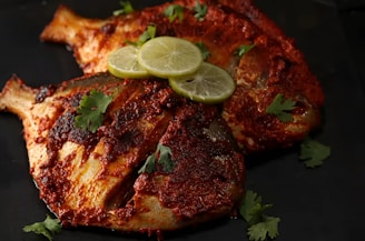 Two spiced fish with lime slices and cilantro