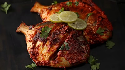 Two seasoned fish with lime slices and cilantro