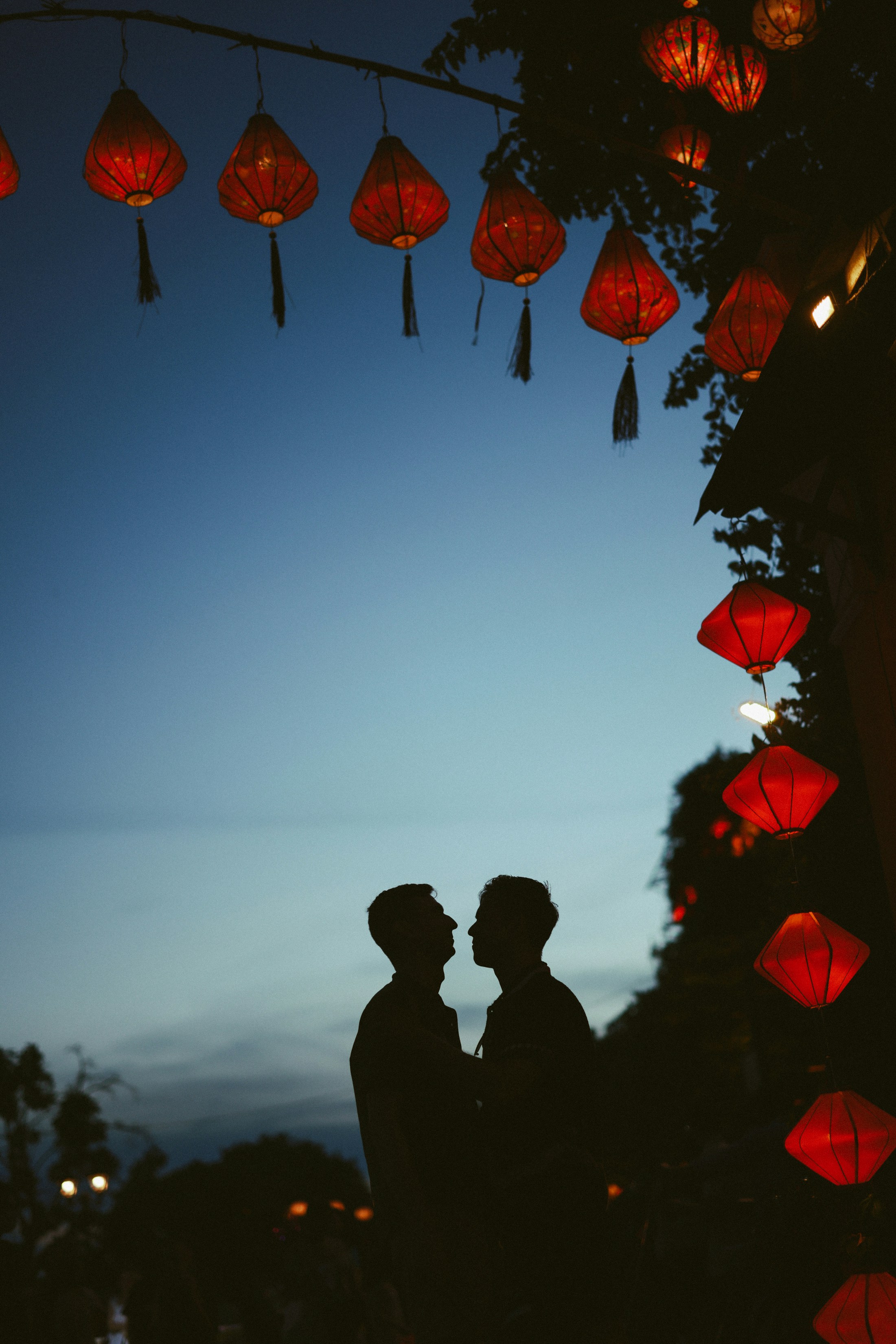 Silhouettes of a couple under red lanterns at dusk