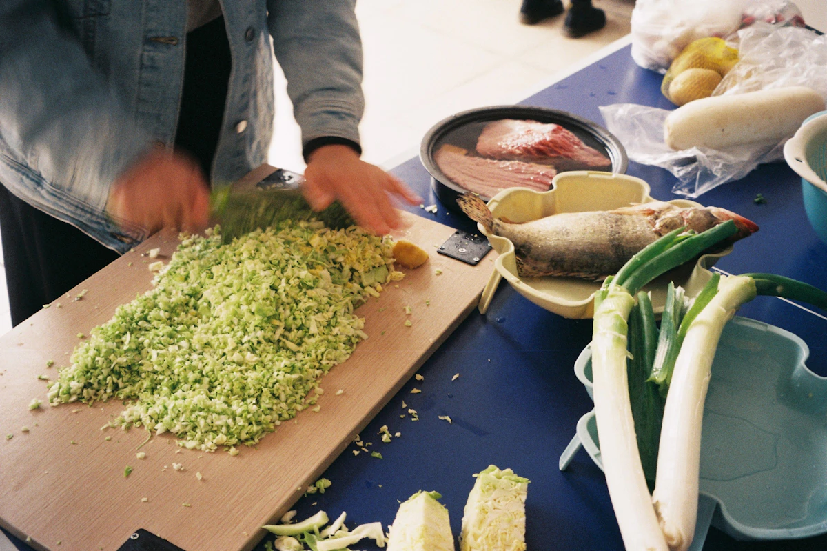 Person chopping fresh vegetables on a wooden cutting board