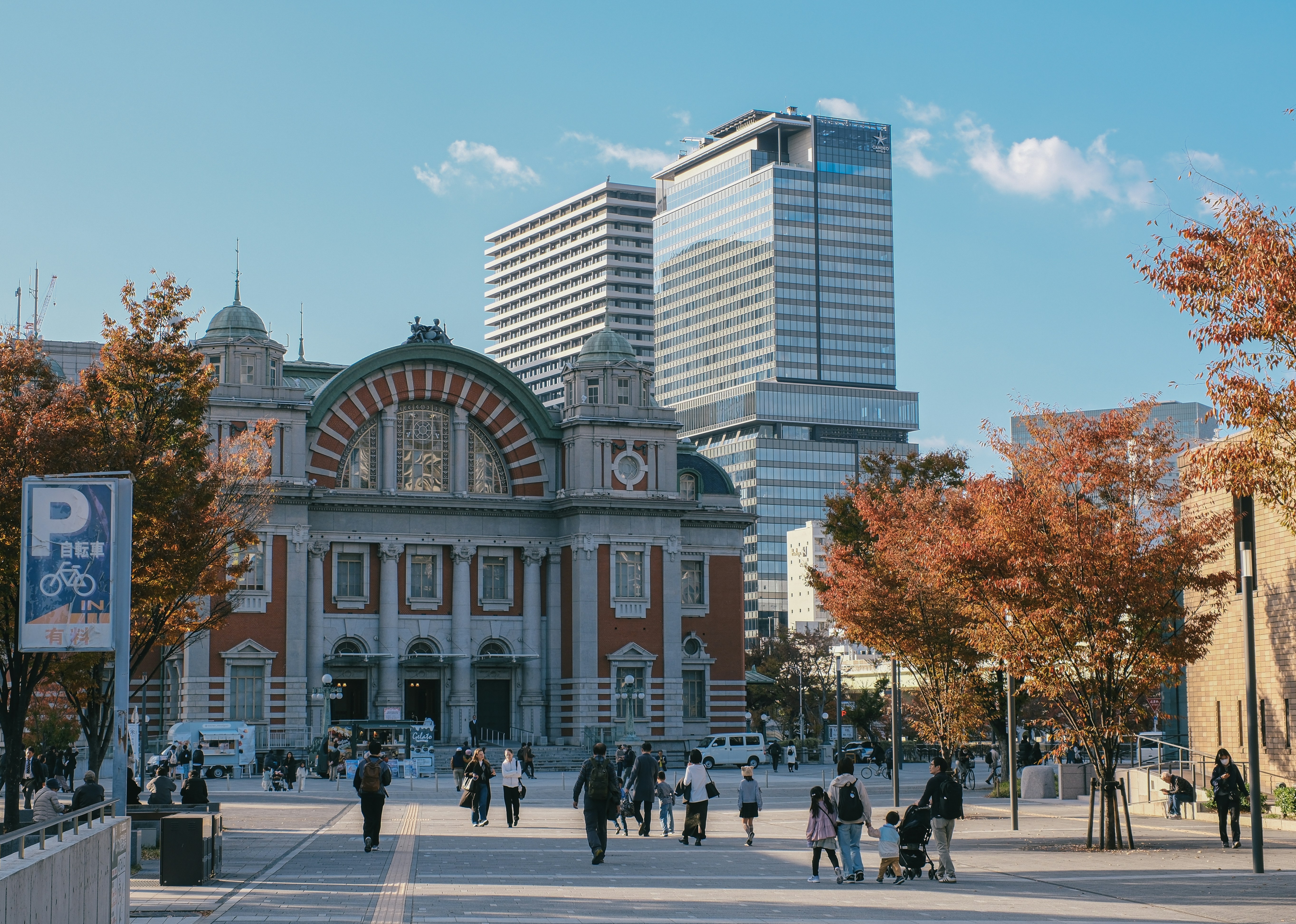 People walking in front of historic building and modern skyscrapers.