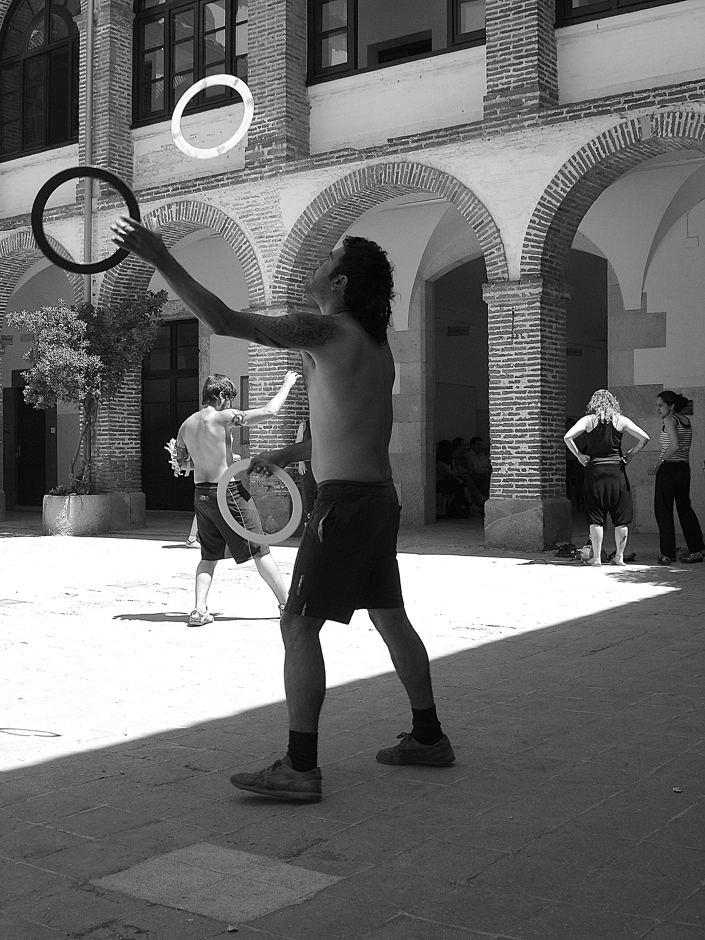 Man juggling rings in a courtyard