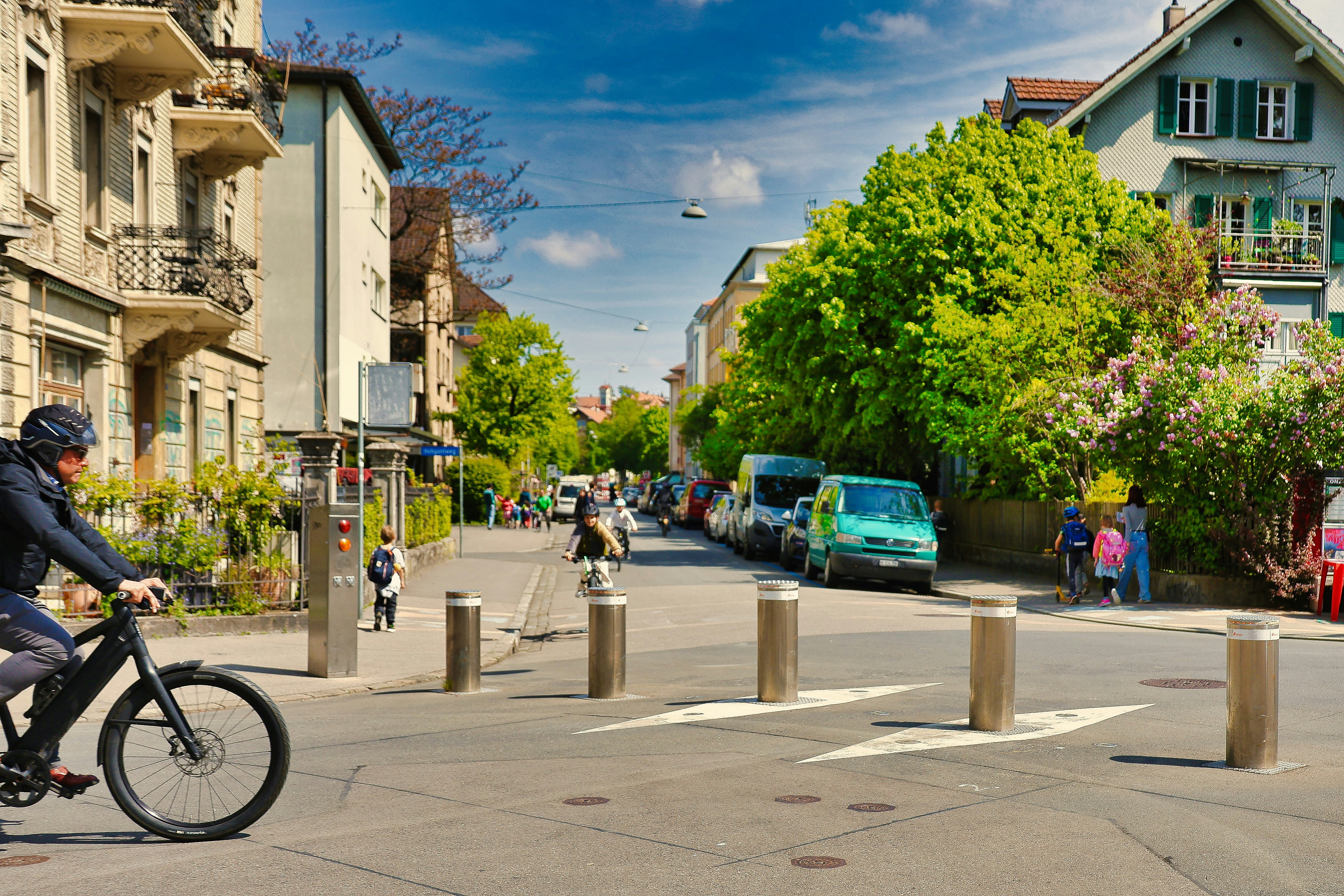 A cyclist rides down a city street with buildings.