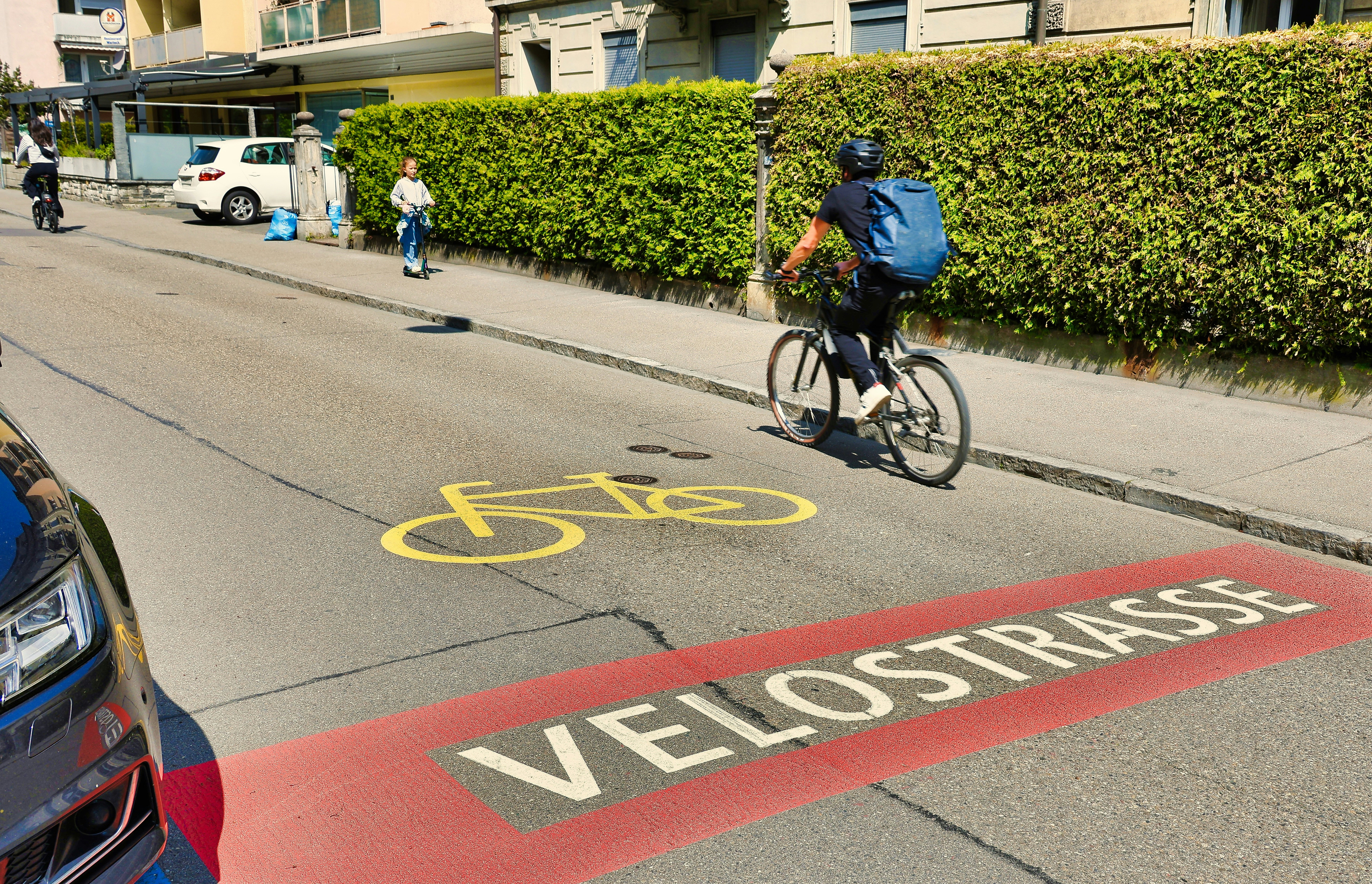 Cyclist on a street with "velostrasse" marking.