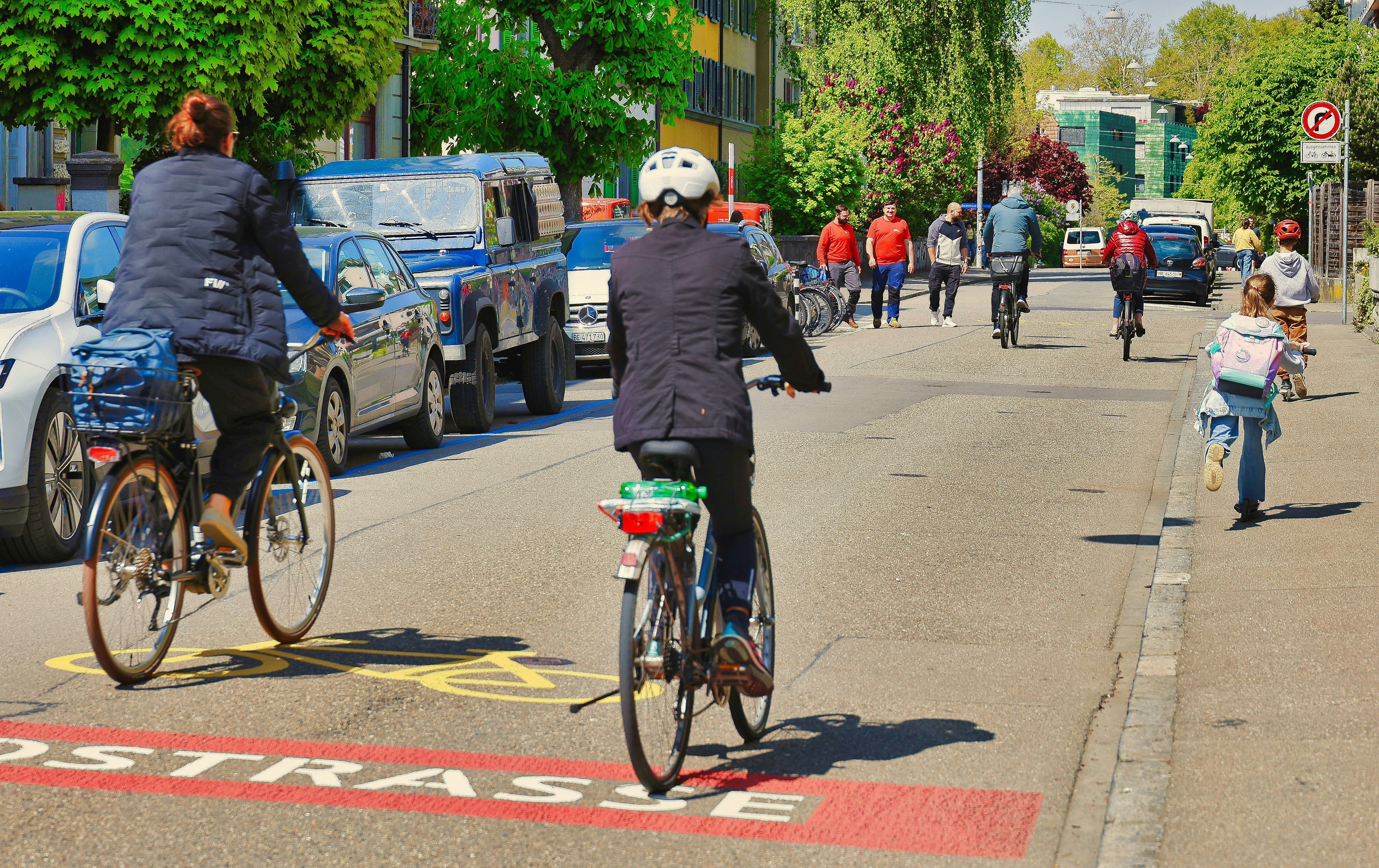 People cycling on a city street with cars.