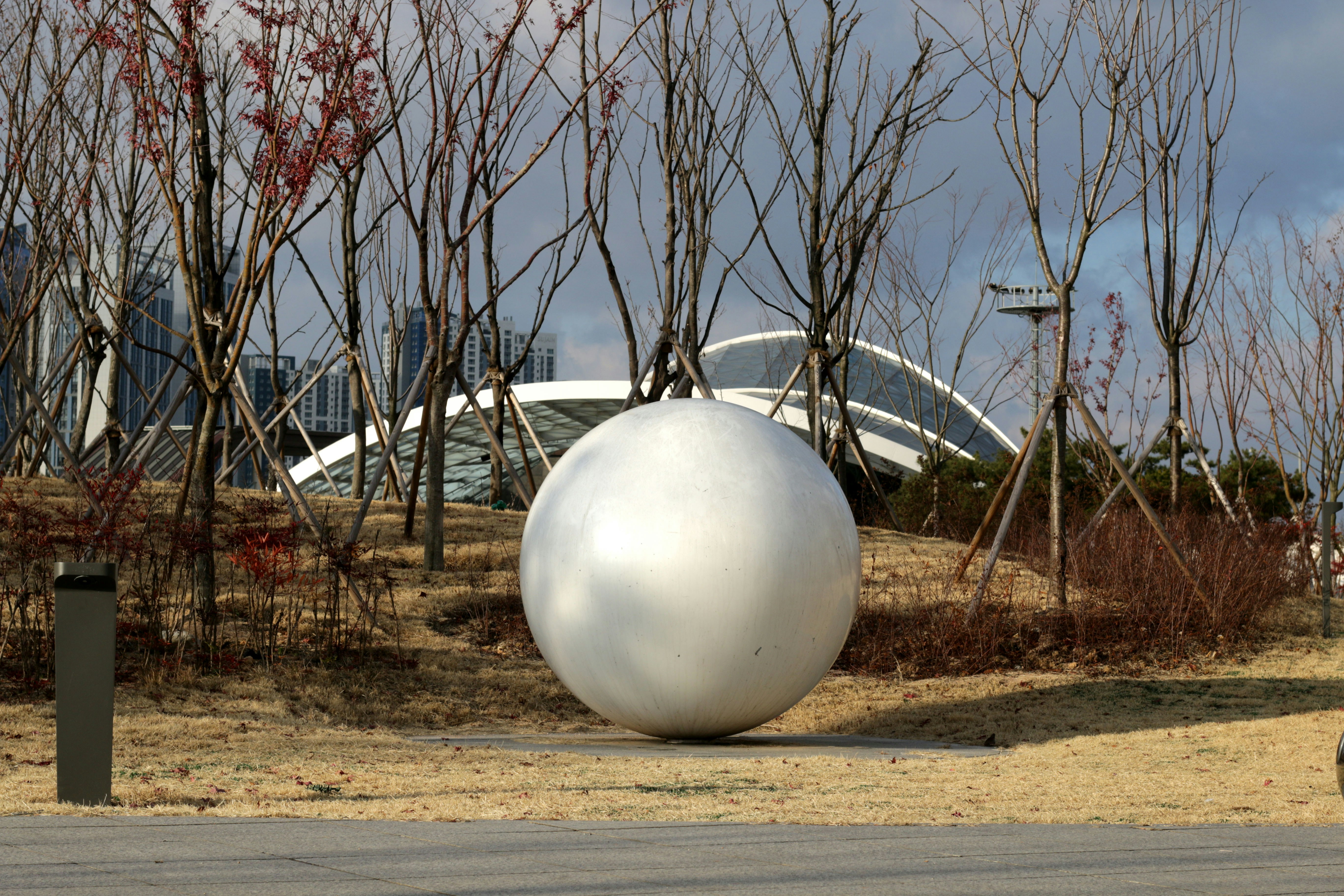 Large white sphere sculpture in a park setting