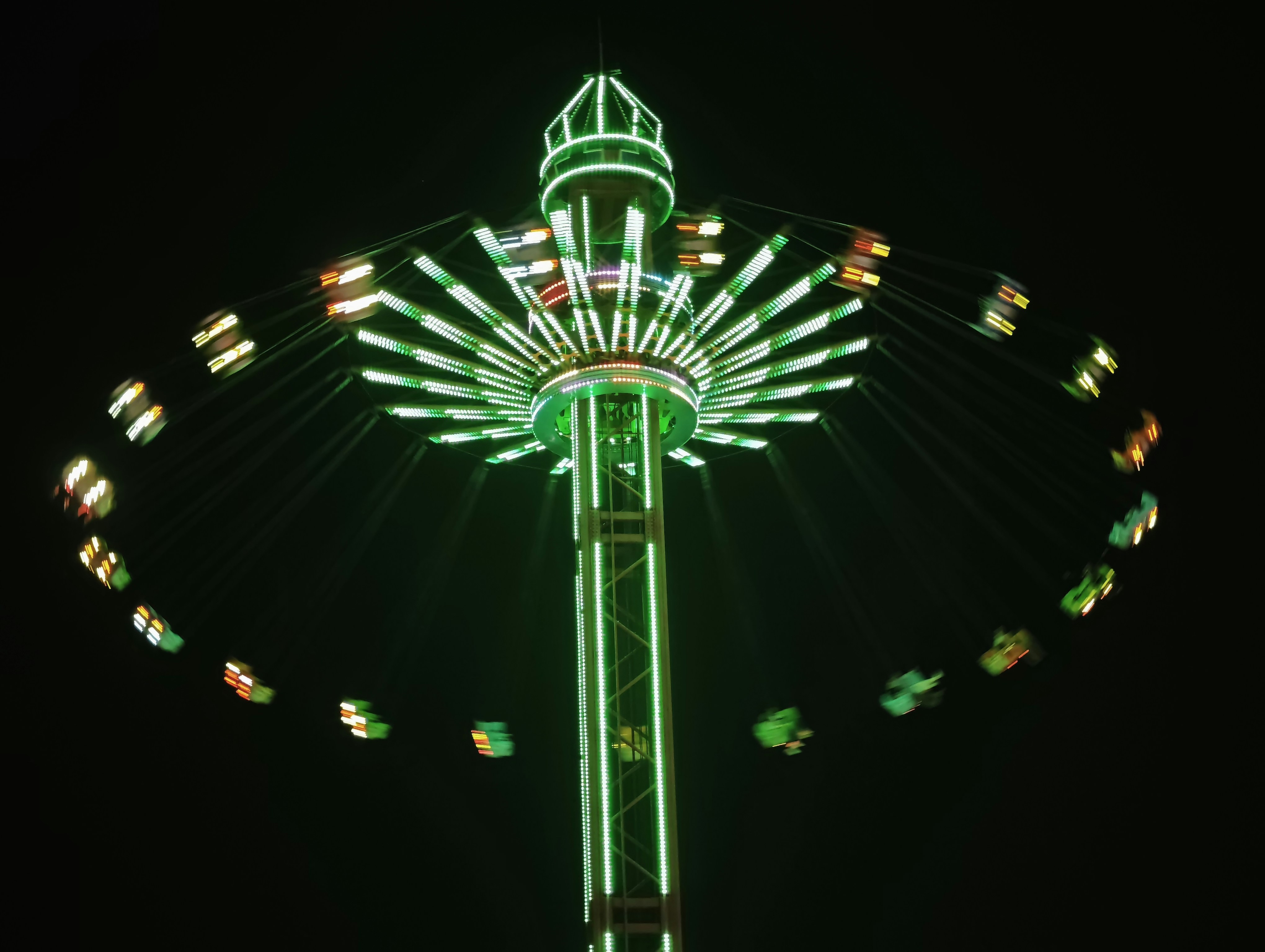 A brightly lit carnival swing ride at night