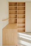 Light wood desk and bookshelf against a wall