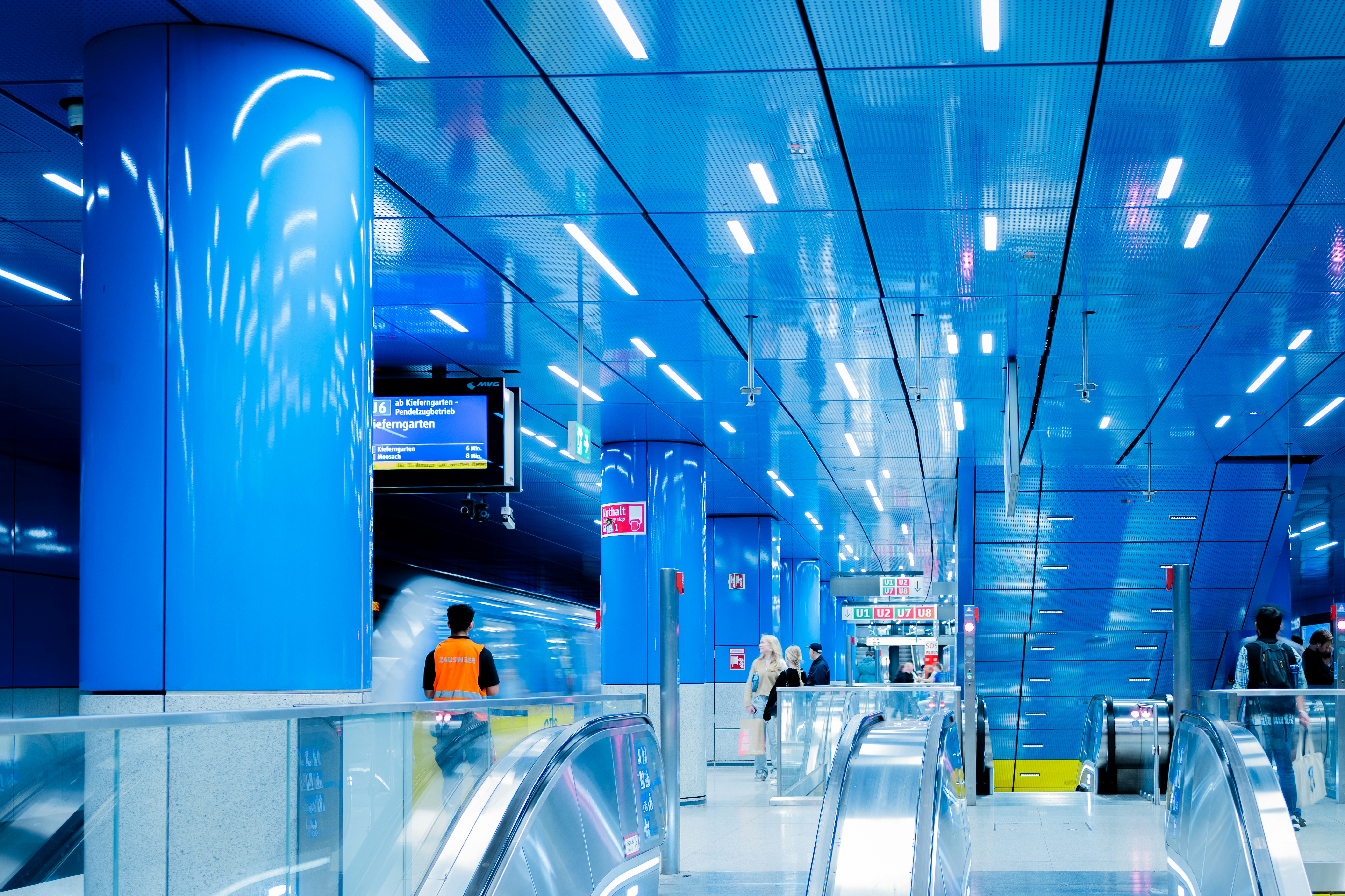 Modern blue subway station with escalators and lights