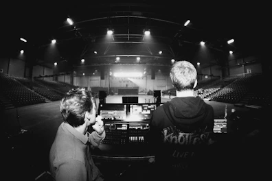 Two people watching a stage in an empty arena.