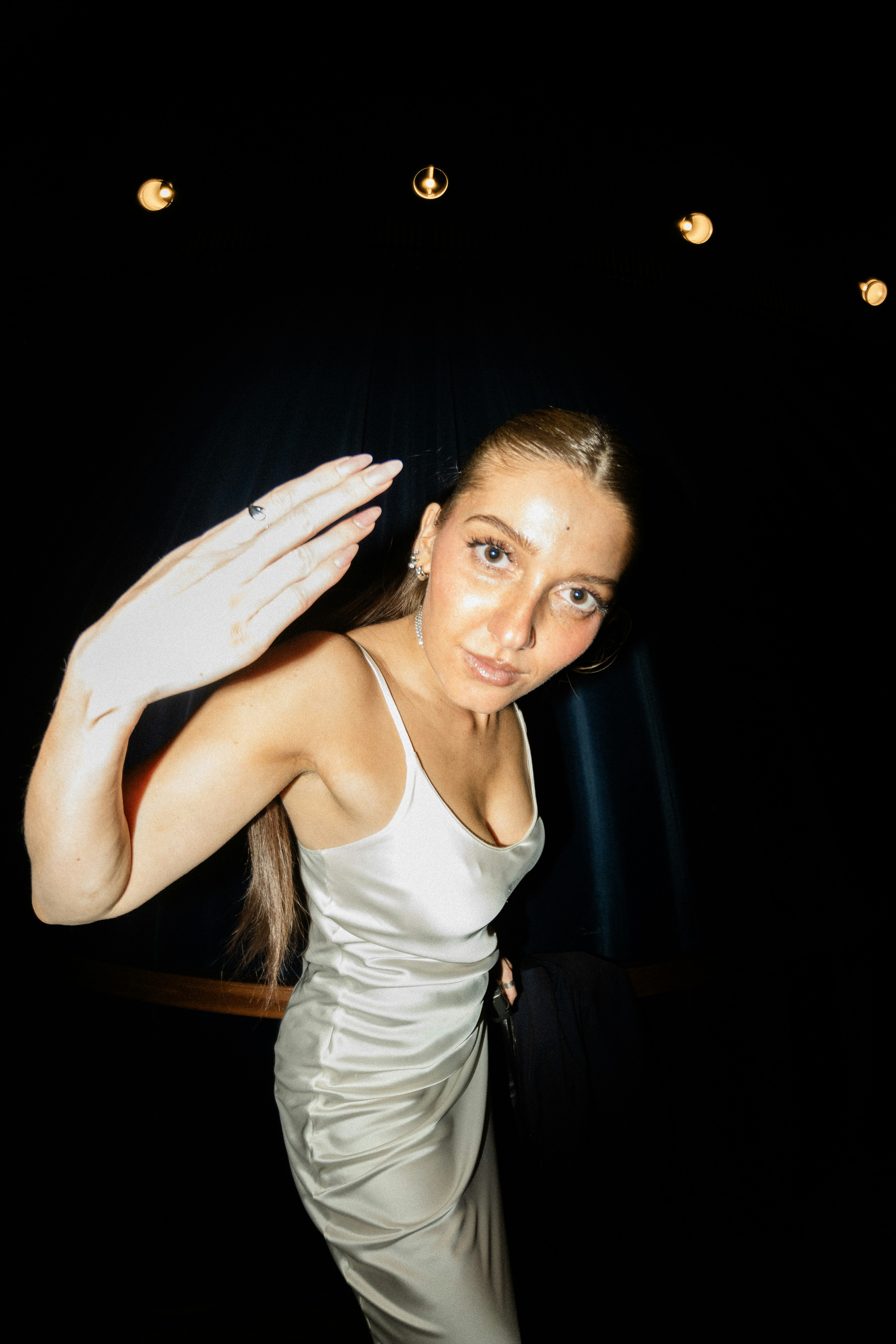 サテンのドレスを着た女性が手を振って挨拶する。