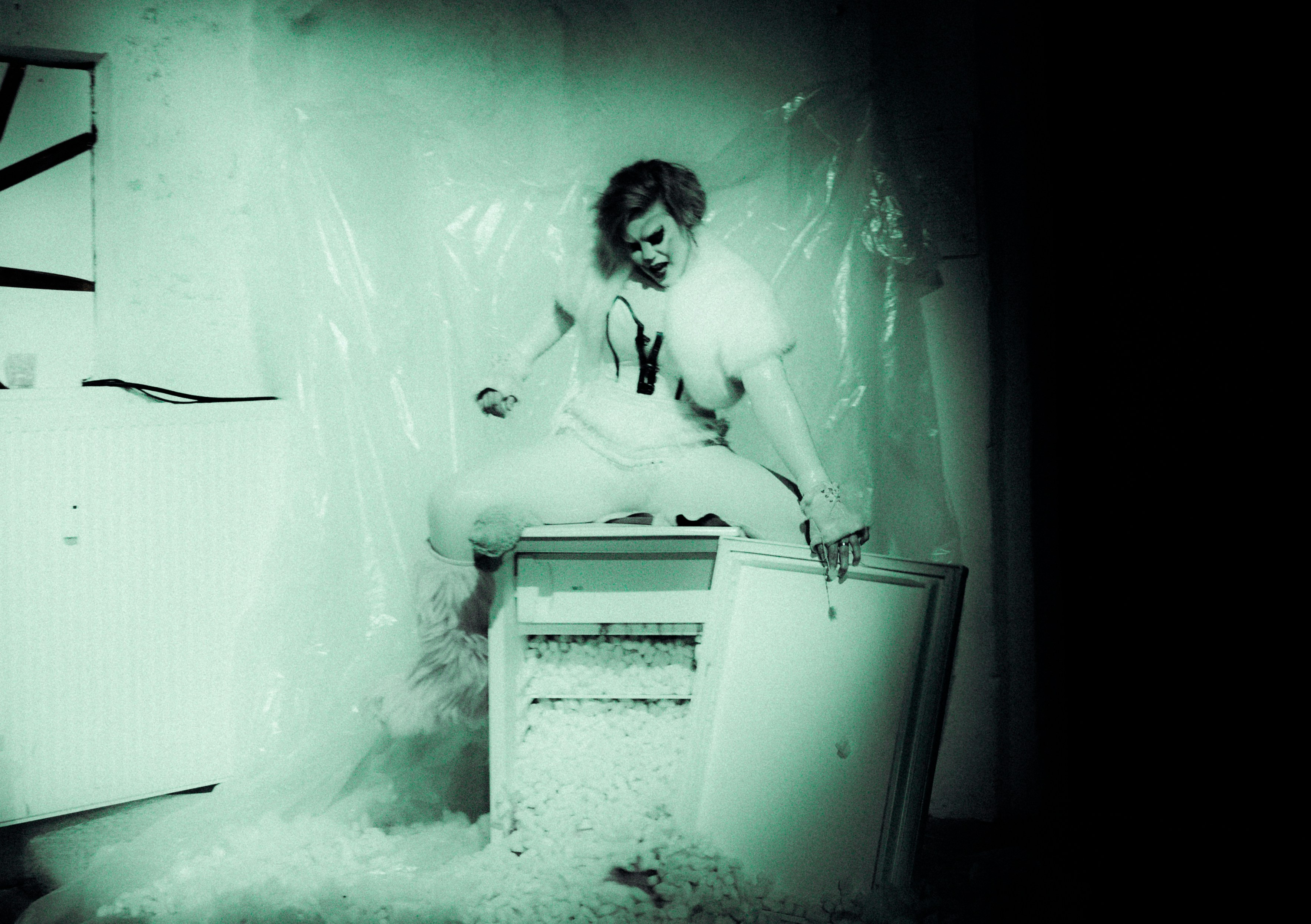 Person sitting on a broken refrigerator with debris.